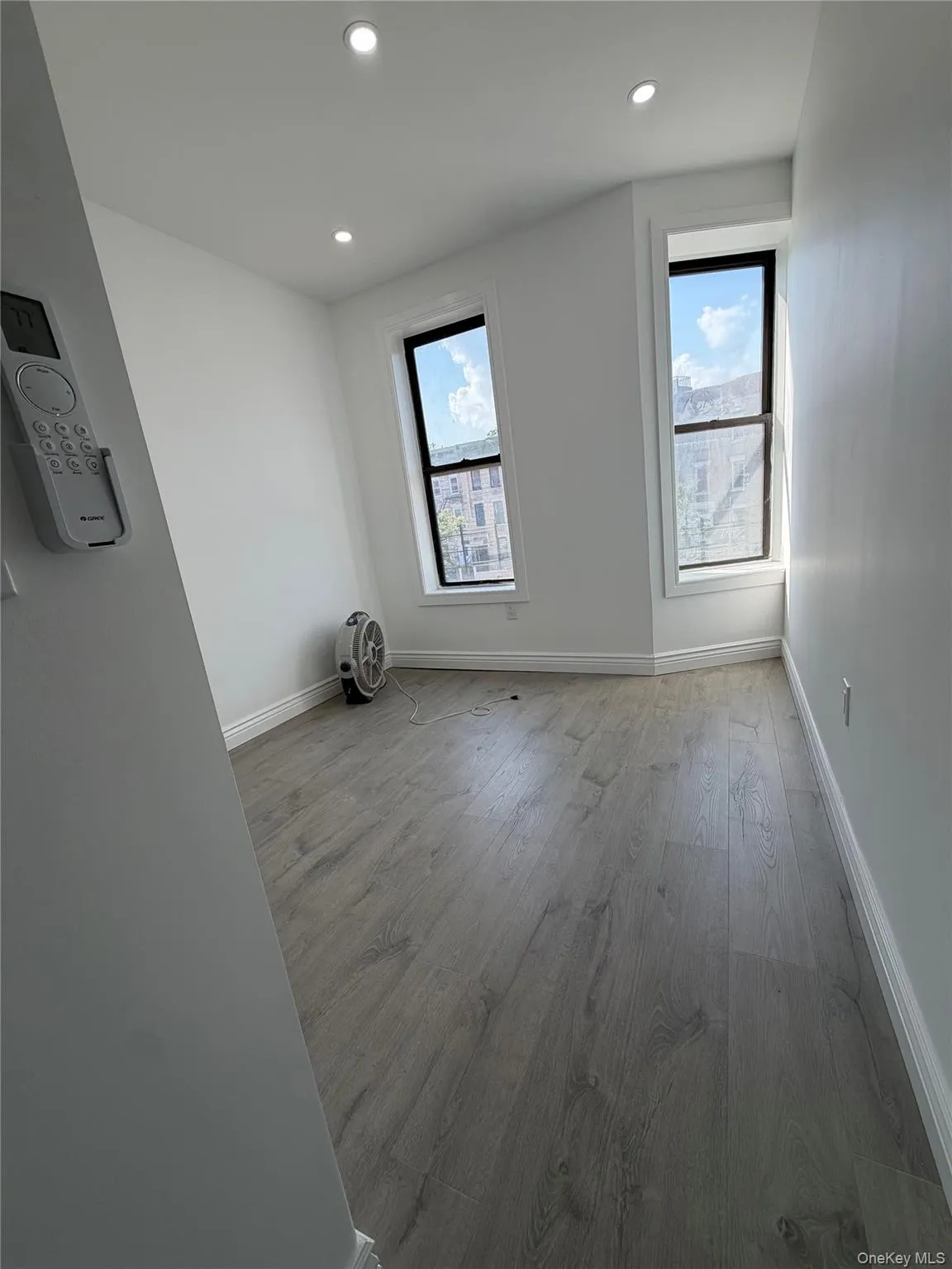 Bright room featuring two windows with dark frames, recessed lighting, wood-finish flooring, and white baseboards Bright room featuring two windows with dark frames, recessed lighting, wood-finish flooring, and white baseboards