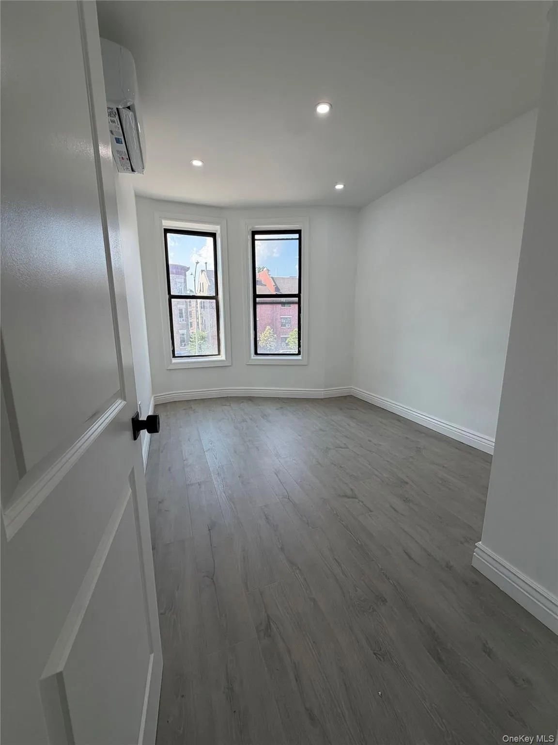 Spacious room featuring wood-finish flooring, recessed lighting, and a split-unit air conditioning system Spacious room featuring wood-finish flooring, recessed lighting, and a split-unit air conditioning system