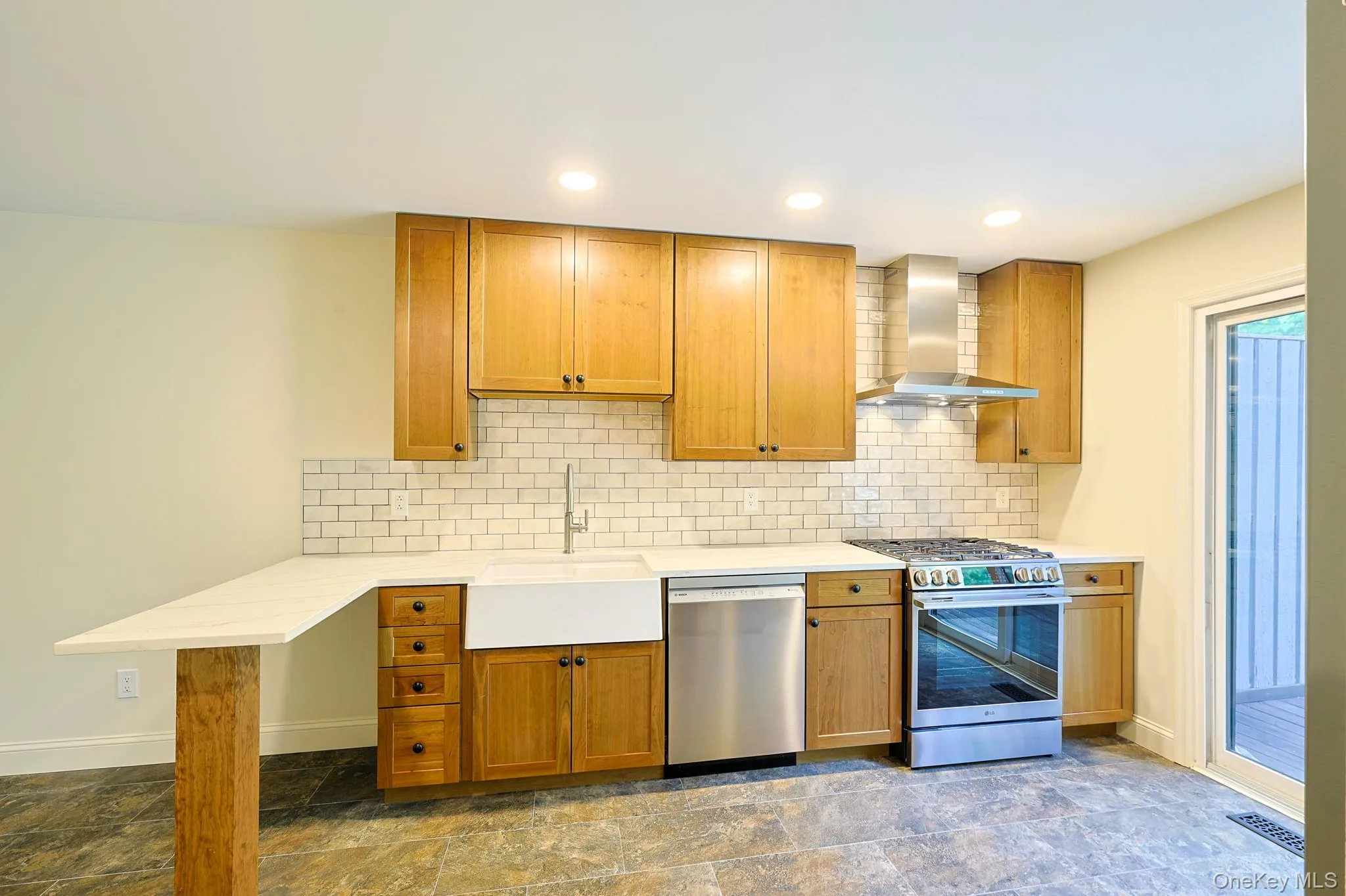 Kitchen featuring natural wood cabinetry, white subway tile backsplash, stainless steel appliances, and a farmhouse sink Kitchen featuring natural wood cabinetry, white subway tile backsplash, stainless steel appliances, and a farmhouse sink