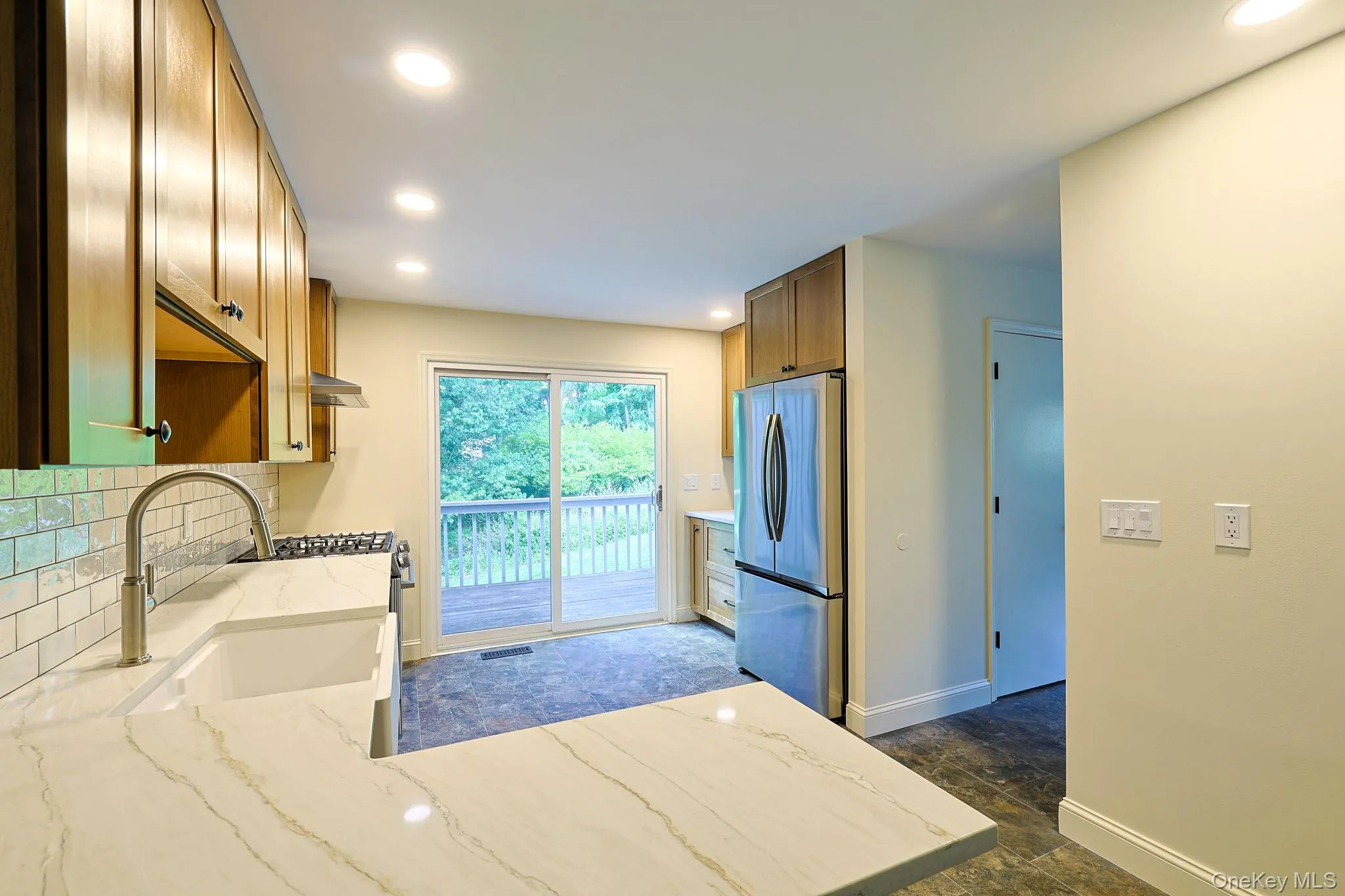 Kitchen featuring wood cabinetry, stainless steel appliances, white quartz countertops, and a subway tile backsplash Kitchen featuring wood cabinetry, stainless steel appliances, white quartz countertops, and a subway tile backsplash