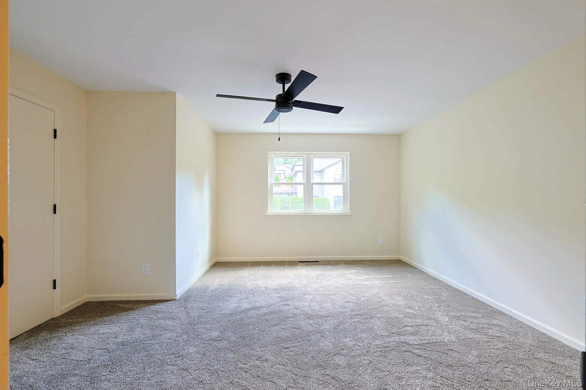 Spacious room featuring neutral carpeting, light-toned walls, and a modern ceiling fan Spacious room featuring neutral carpeting, light-toned walls, and a modern ceiling fan