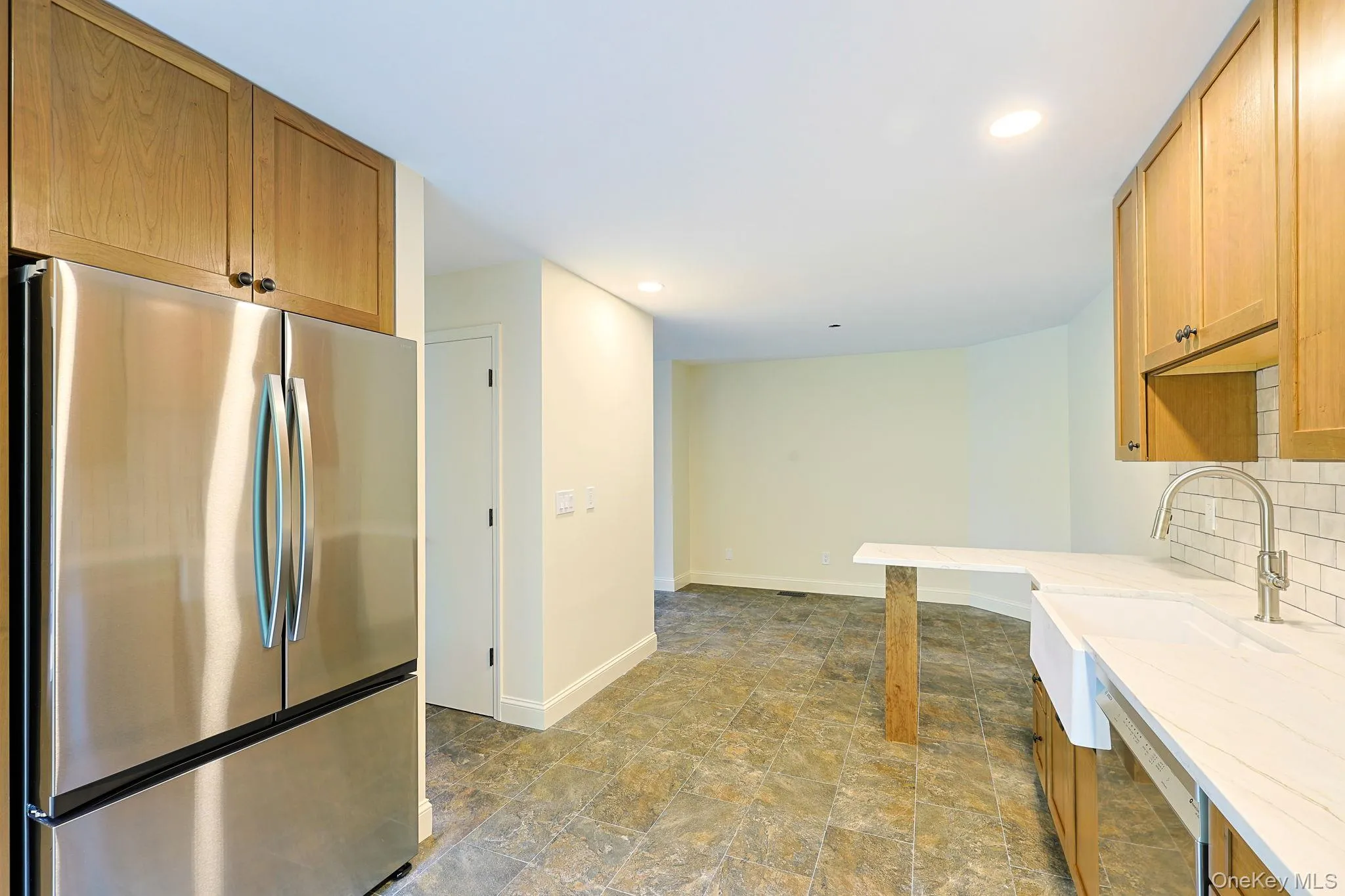 Kitchen featuring stainless steel French-door refrigerator, light wood cabinetry, subway tile backsplash, and a farmhouse sink Kitchen featuring stainless steel French-door refrigerator, light wood cabinetry, subway tile backsplash, and a farmhouse sink