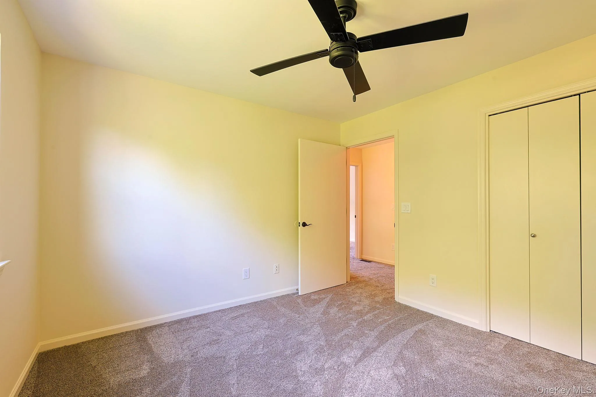 Second Bedroom. Neutral-toned room featuring a ceiling fan, light-colored walls, grey carpeting, a single window, and bi-fold closet doors Second Bedroom. Neutral-toned room featuring a ceiling fan, light-colored walls, grey carpeting, a single window, and bi-fold closet doors