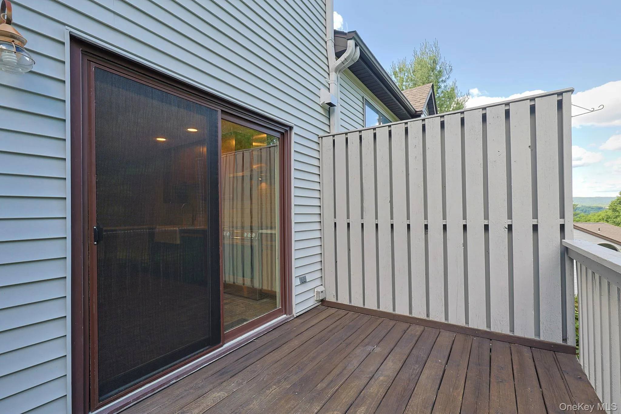 Wood-finish deck with privacy fencing and sliding glass door access Wood-finish deck with privacy fencing and sliding glass door access