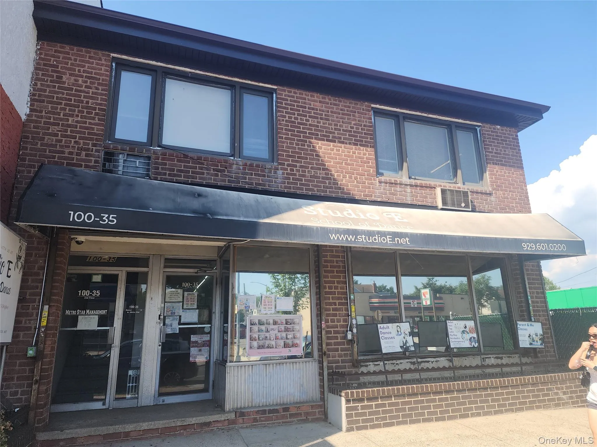 Brick facade building featuring a ground-level storefront with large display windows and a dark awning Brick facade building featuring a ground-level storefront with large display windows and a dark awning