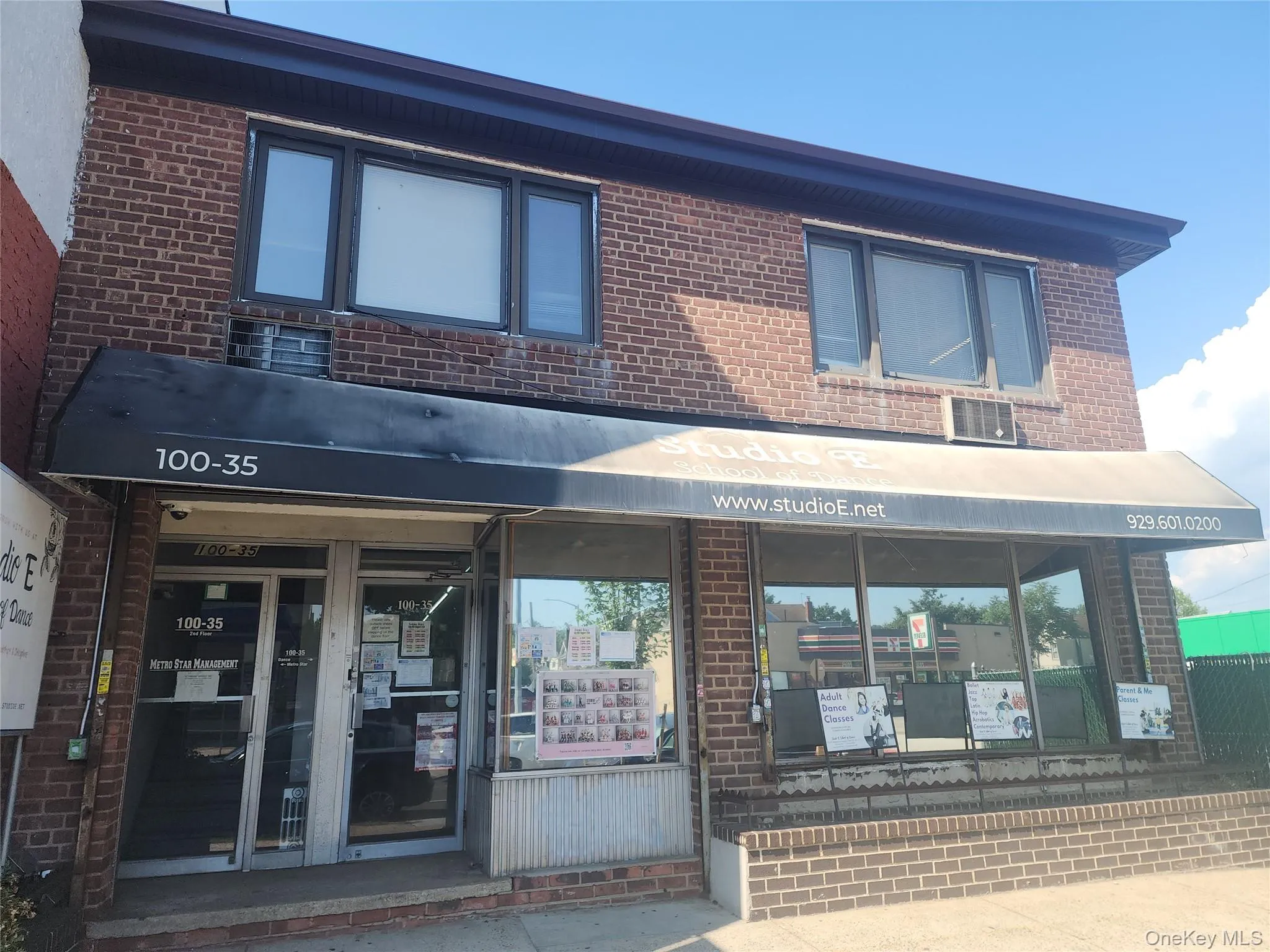 Brick facade building featuring a black awning, multiple windows, and a glass storefront entrance Brick facade building featuring a black awning, multiple windows, and a glass storefront entrance