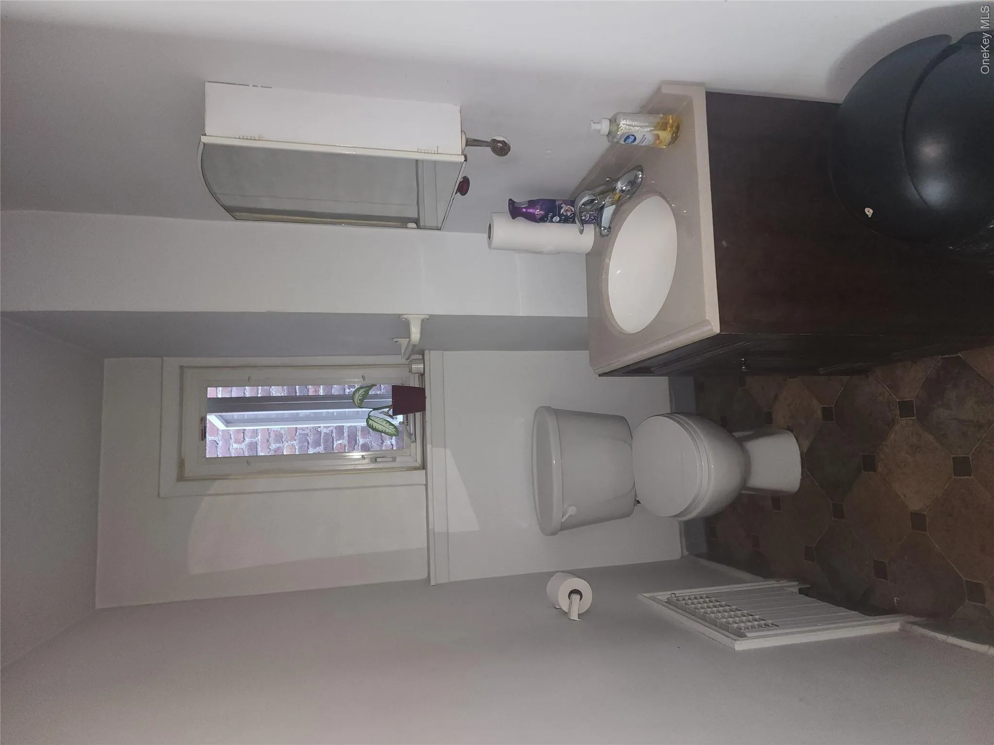 Compact bathroom featuring a white toilet, single vanity with a light-colored countertop, and a medicine cabinet with mirrored door Compact bathroom featuring a white toilet, single vanity with a light-colored countertop, and a medicine cabinet with mirrored door