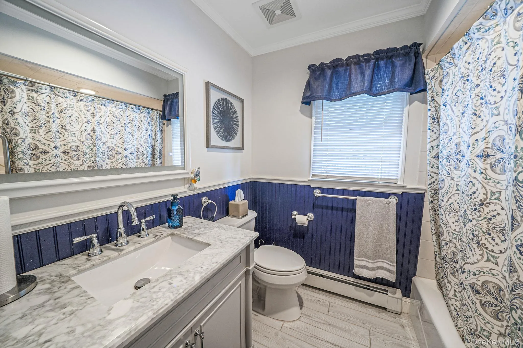 Bathroom featuring a single vanity with a rectangular sink, a light-toned countertop, and chrome fixtures Bathroom featuring a single vanity with a rectangular sink, a light-toned countertop, and chrome fixtures