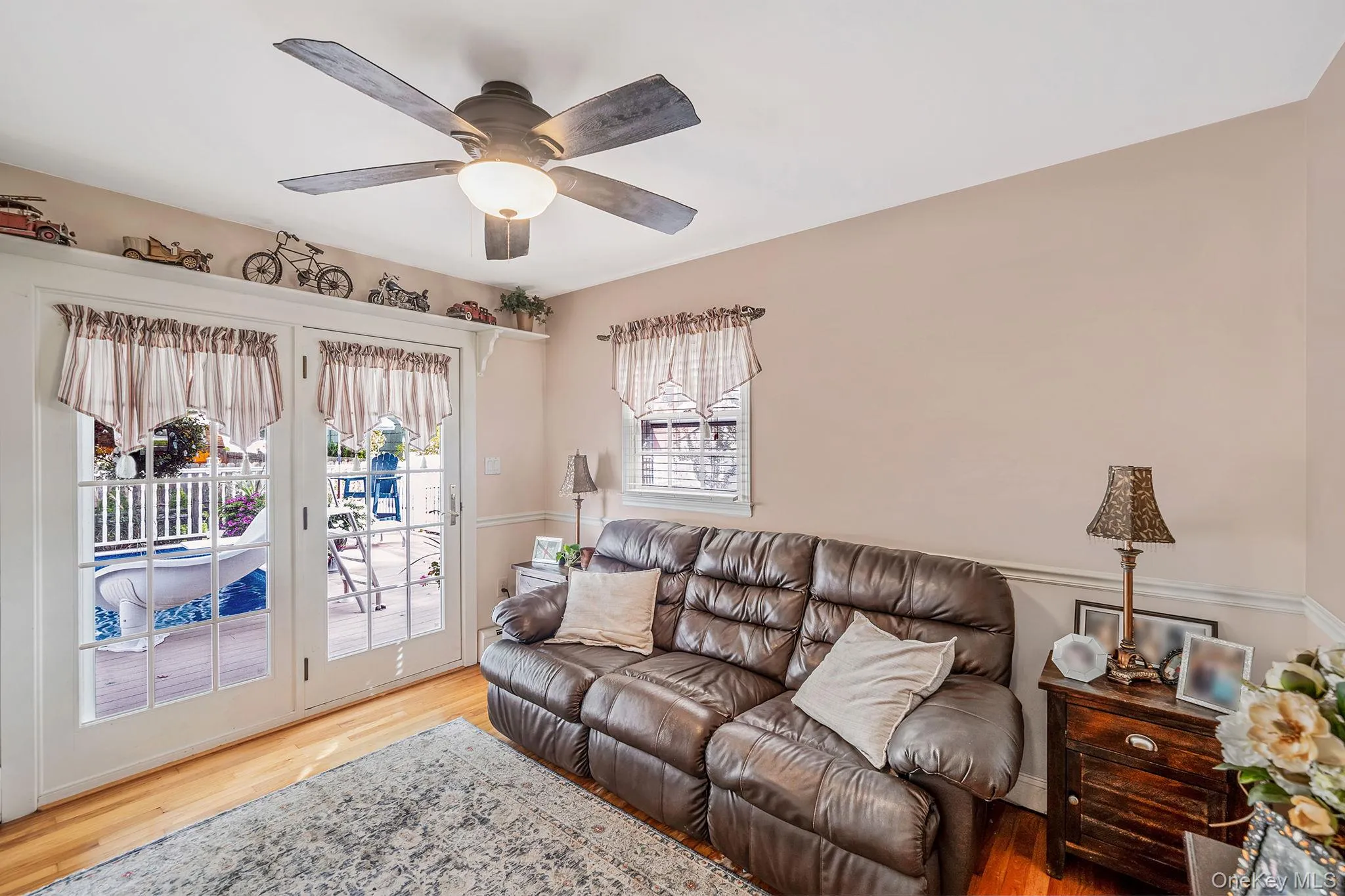 Den/Bedroom with french doors opening to deck and pool area, complemented by wood-finish flooring and a ceiling fan with integrated lighting Den/Bedroom with french doors opening to deck and pool area, complemented by wood-finish flooring and a ceiling fan with integrated lighting