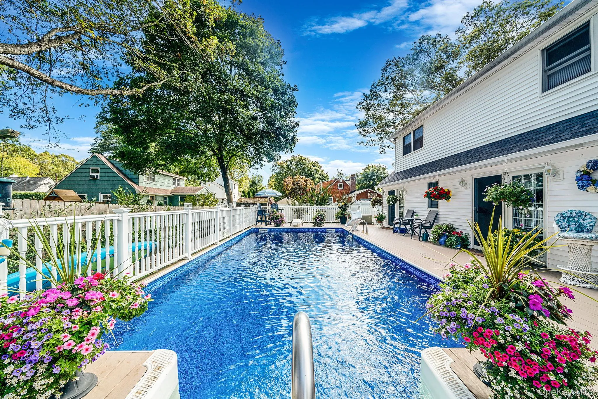 Rectangular in-ground swimming pool with a white vinyl fence and a light-colored decking surround Rectangular in-ground swimming pool with a white vinyl fence and a light-colored decking surround