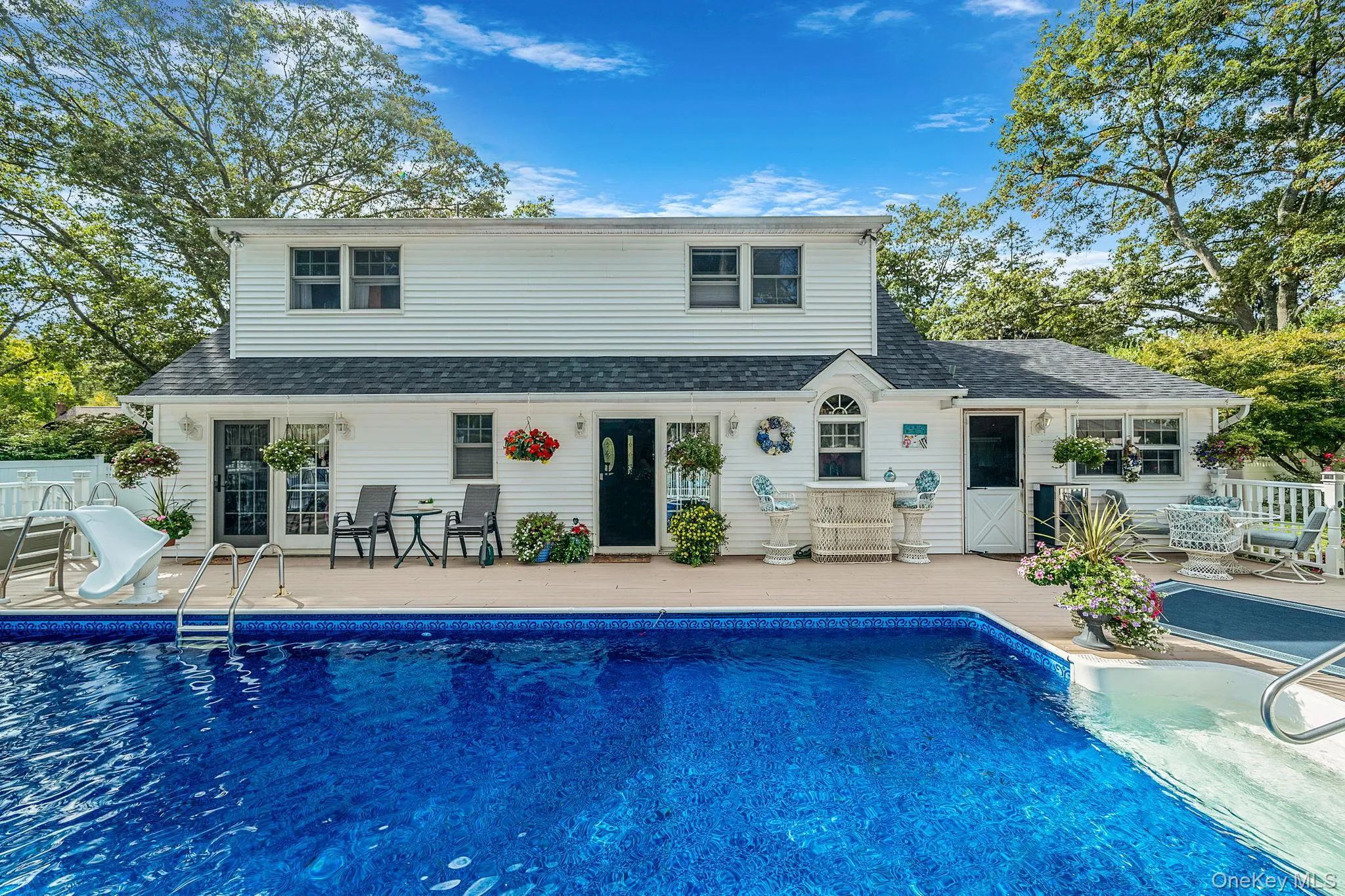 Backyard oasis featuring a large inground swimming pool with an integrated slide Backyard oasis featuring a large inground swimming pool with an integrated slide