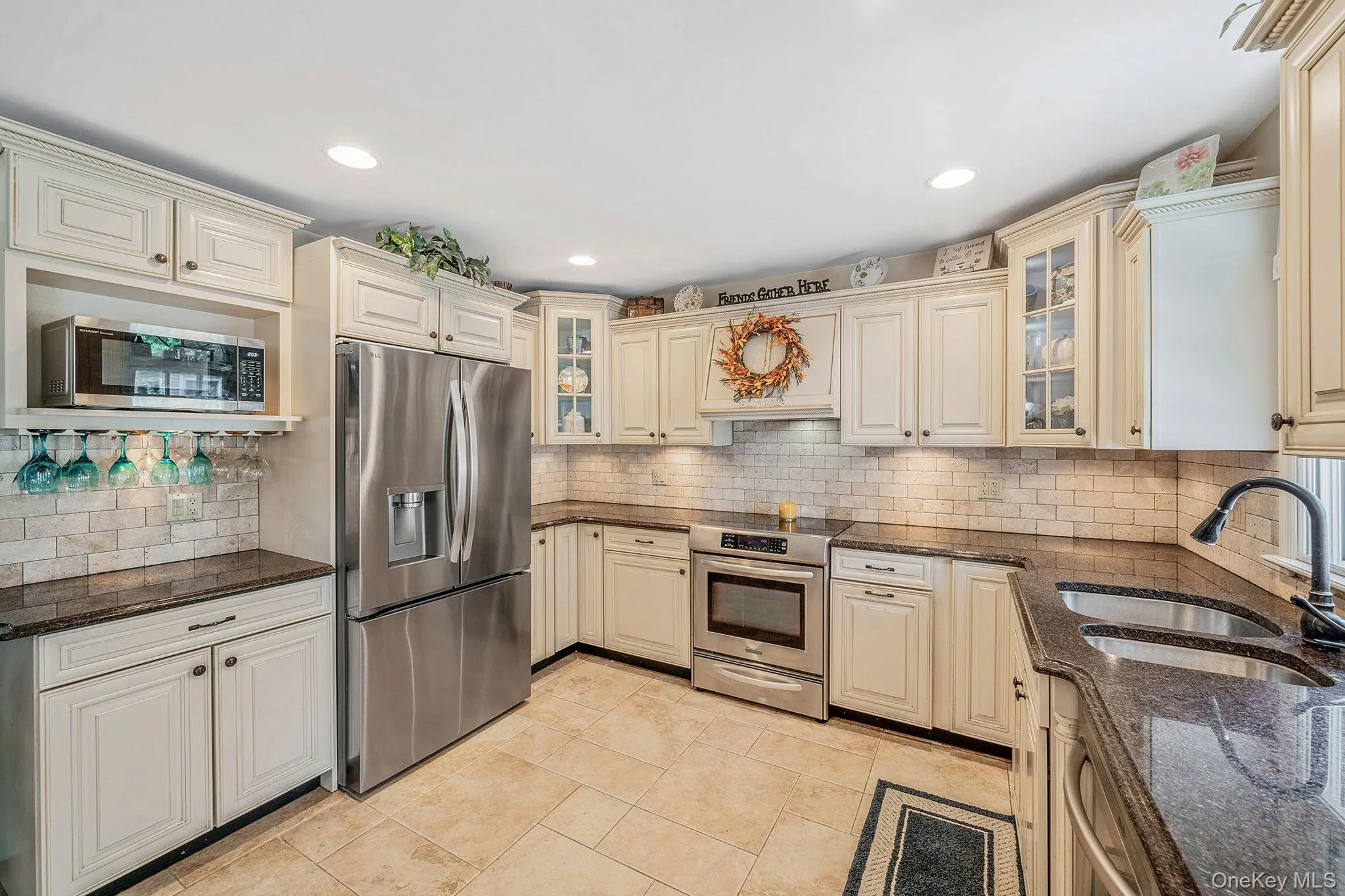 U-shaped kitchen featuring cream cabinetry, dark stone countertops, stainless steel appliances, subway tile backsplash, and recessed lighting U-shaped kitchen featuring cream cabinetry, dark stone countertops, stainless steel appliances, subway tile backsplash, and recessed lighting