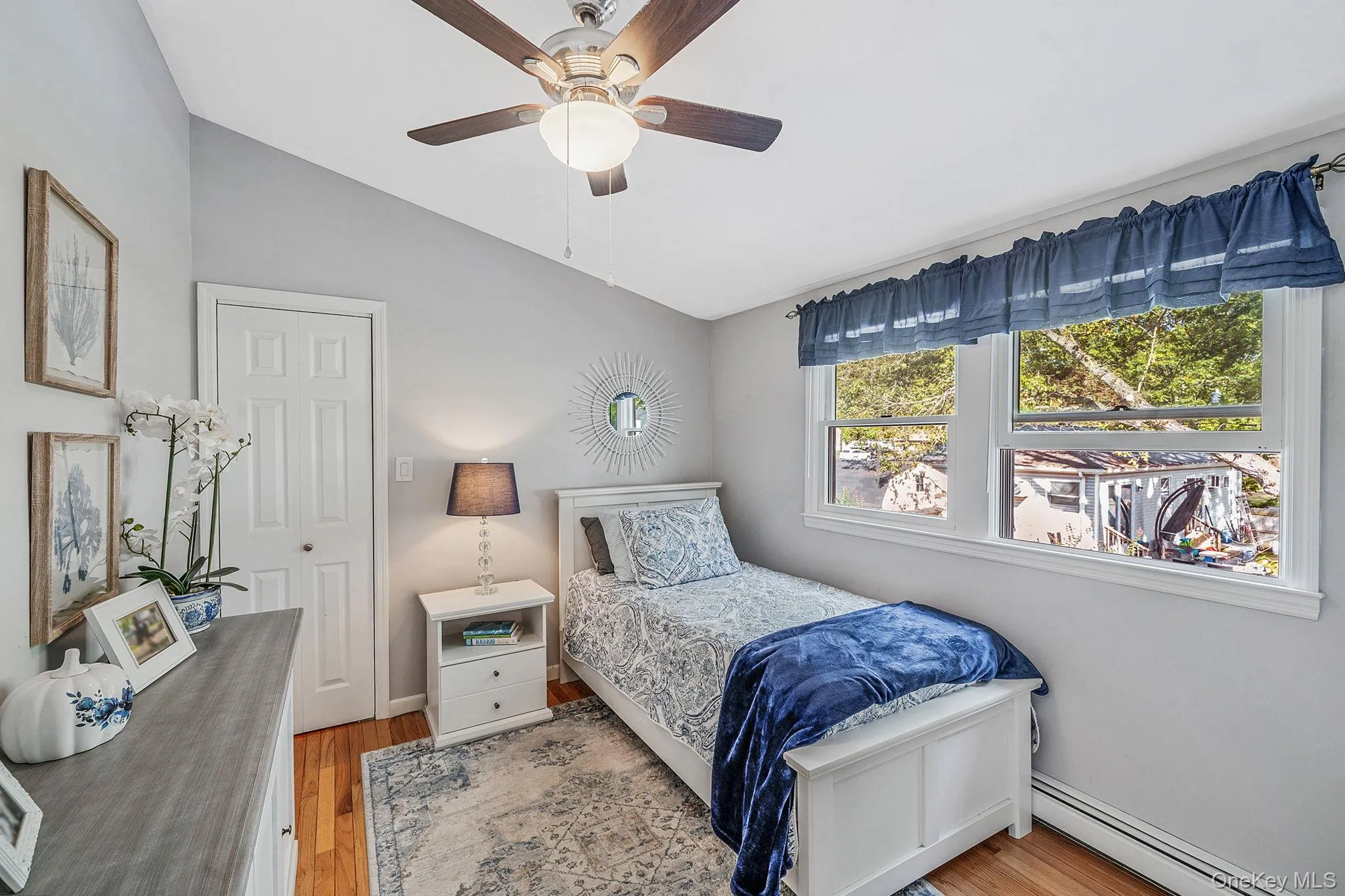 Bright room featuring light gray walls, wood-finish flooring, a ceiling fan with integrated lighting, and a white paneled door Bright room featuring light gray walls, wood-finish flooring, a ceiling fan with integrated lighting, and a white paneled door