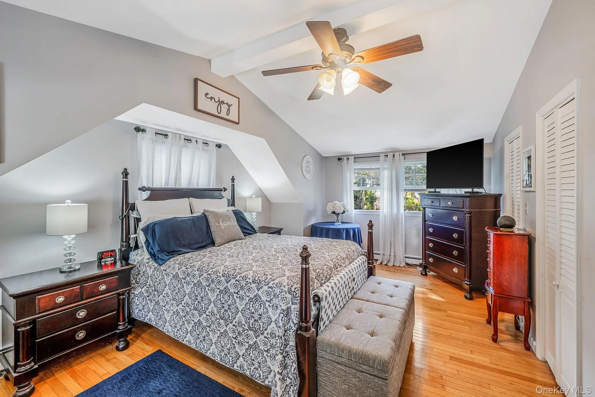 Bedroom featuring wood-finish flooring, a ceiling fan with integrated lighting, and sloped ceilings Bedroom featuring wood-finish flooring, a ceiling fan with integrated lighting, and sloped ceilings