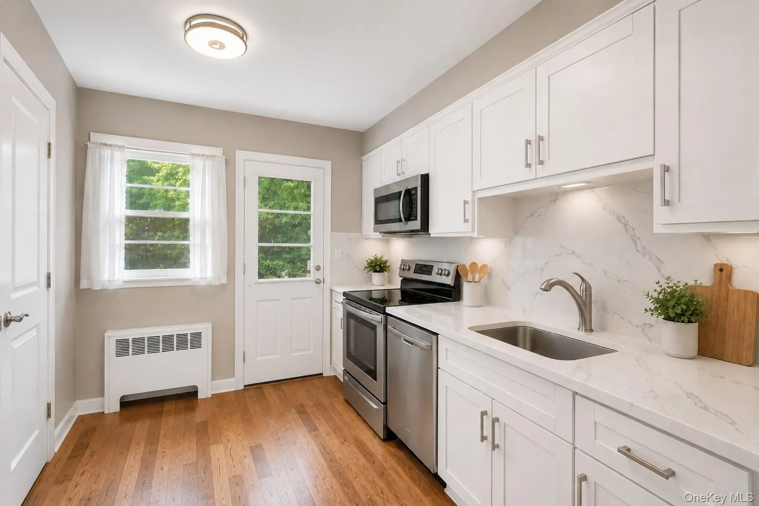 Virtually rendered. Kitchen featuring white cabinetry, stainless steel appliances, a single basin sink with a gooseneck faucet, quartz countertops and luxury vinyl wood-finish flooring Virtually rendered. Kitchen featuring white cabinetry, stainless steel appliances, a single basin sink with a gooseneck faucet, quartz countertops and luxury vinyl wood-finish flooring