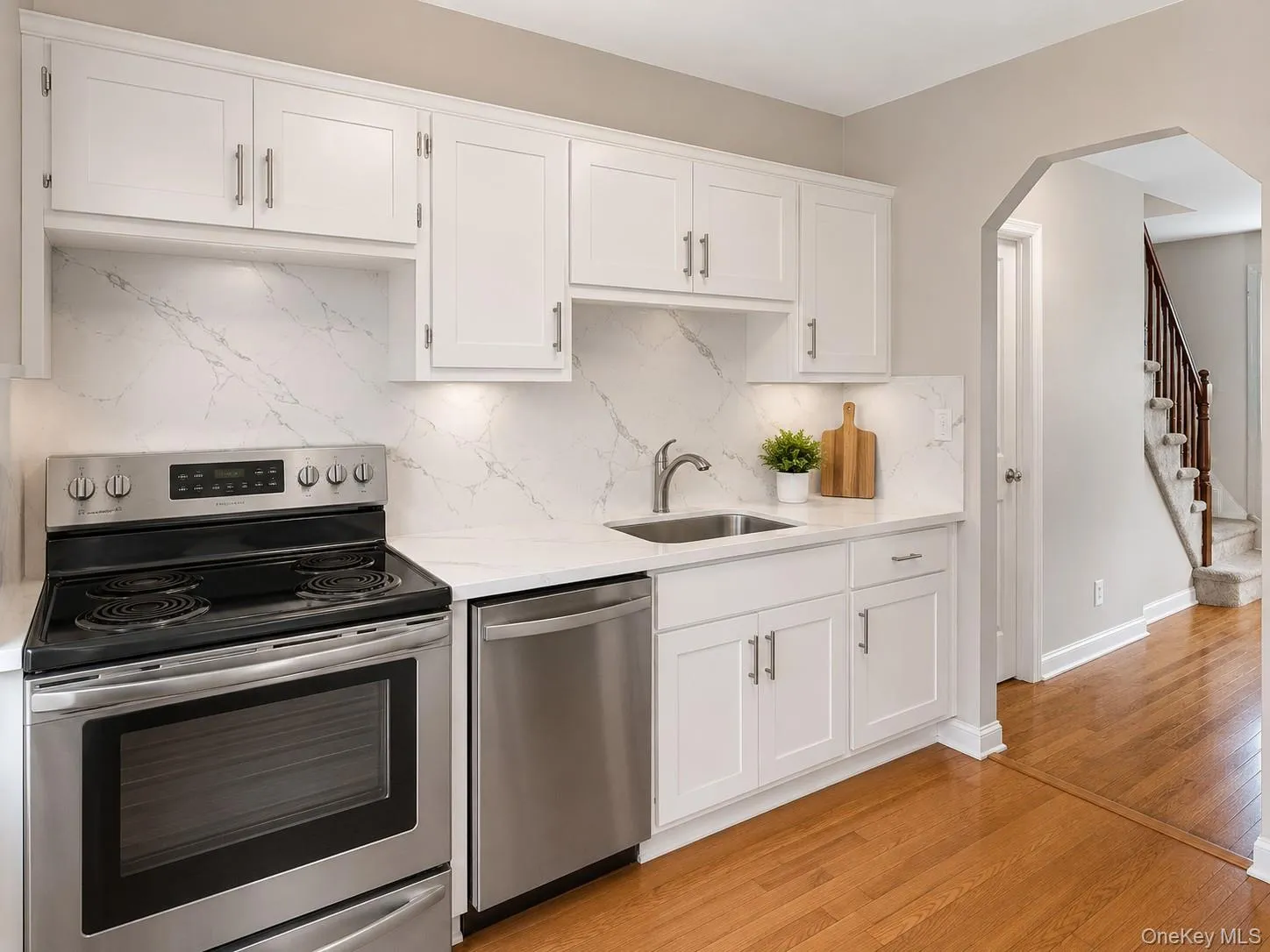 Virtually Rendered. Kitchen featuring stainless steel range, stainless steel dishwasher, undermount sink, white cabinetry with brushed nickel hardware, and a quartz countertop and backsplash Virtually Rendered. Kitchen featuring stainless steel range, stainless steel dishwasher, undermount sink, white cabinetry with brushed nickel hardware, and a quartz countertop and backsplash