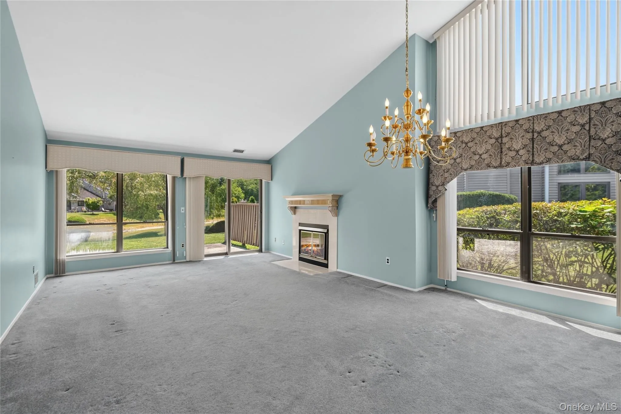 Spacious living area featuring a vaulted ceiling and a gold-tone chandelier Spacious living area featuring a vaulted ceiling and a gold-tone chandelier