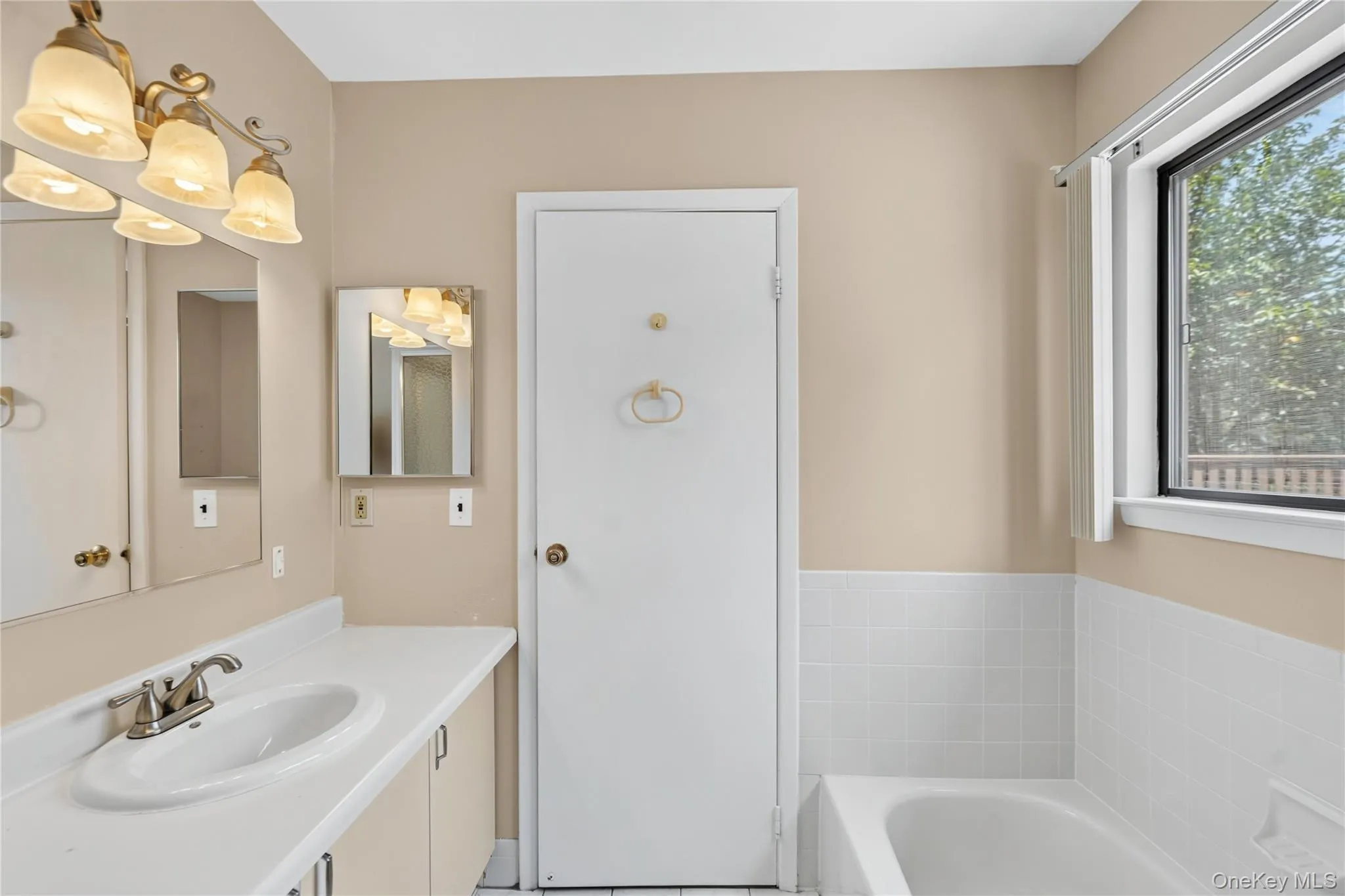 Bathroom featuring a white vanity with an integrated sink, brushed nickel faucet, and overhead vanity lighting Bathroom featuring a white vanity with an integrated sink, brushed nickel faucet, and overhead vanity lighting