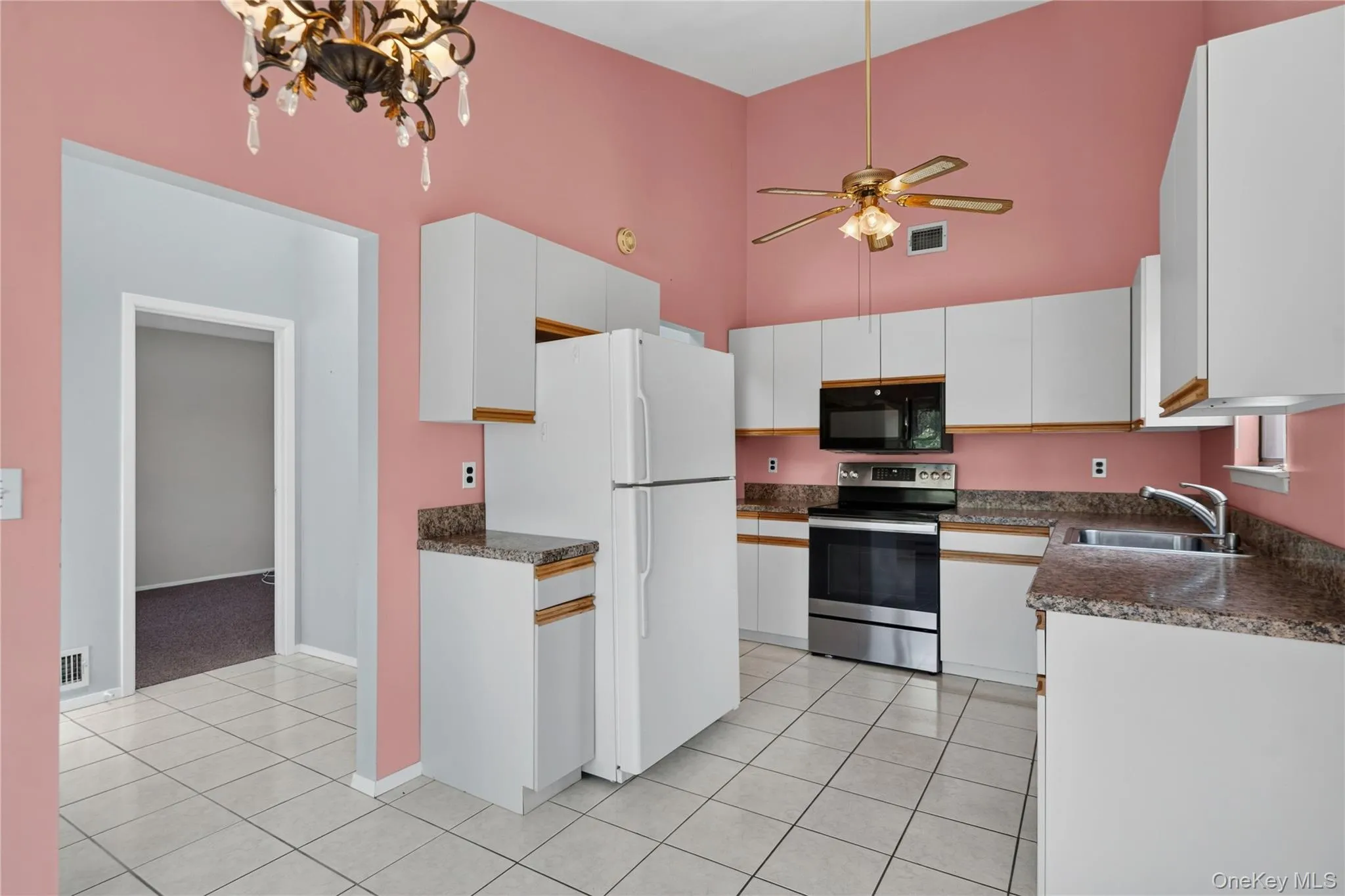 Kitchen featuring white cabinetry, stone-finish countertops, stainless steel appliances, and tile flooring Kitchen featuring white cabinetry, stone-finish countertops, stainless steel appliances, and tile flooring
