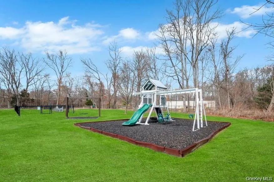 Outdoor playset featuring slides and swings on a dark ground cover Outdoor playset featuring slides and swings on a dark ground cover