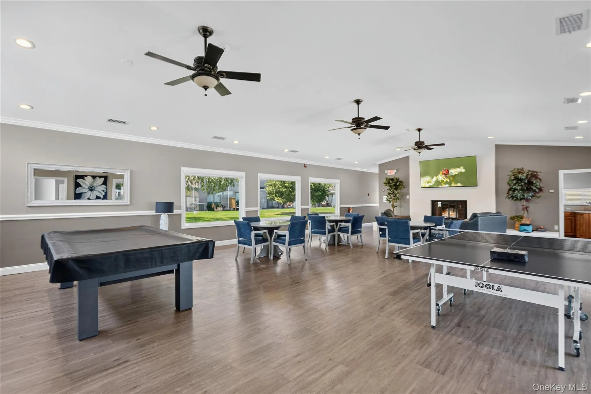 Spacious recreational room featuring wood-finish flooring and multiple ceiling fans Spacious recreational room featuring wood-finish flooring and multiple ceiling fans