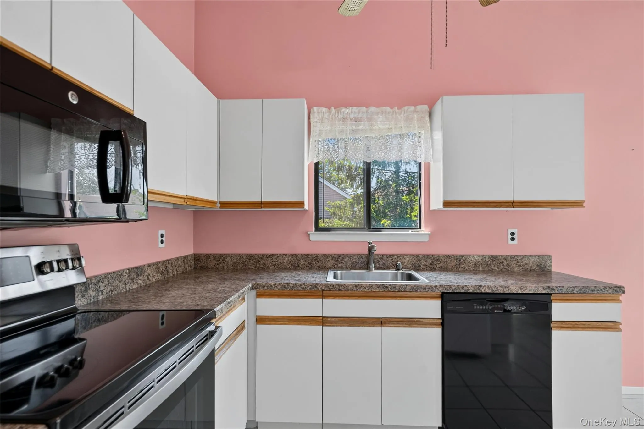 Kitchen featuring white upper and lower cabinetry, laminate countertops, stainless steel sink, and black appliances Kitchen featuring white upper and lower cabinetry, laminate countertops, stainless steel sink, and black appliances