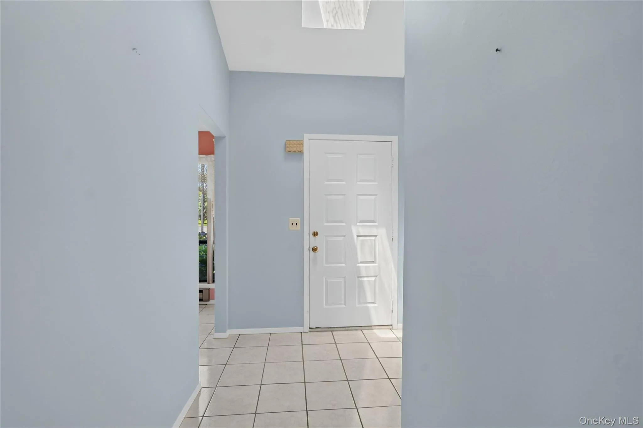 Entryway featuring a paneled door, tiled flooring, and a skylight Entryway featuring a paneled door, tiled flooring, and a skylight