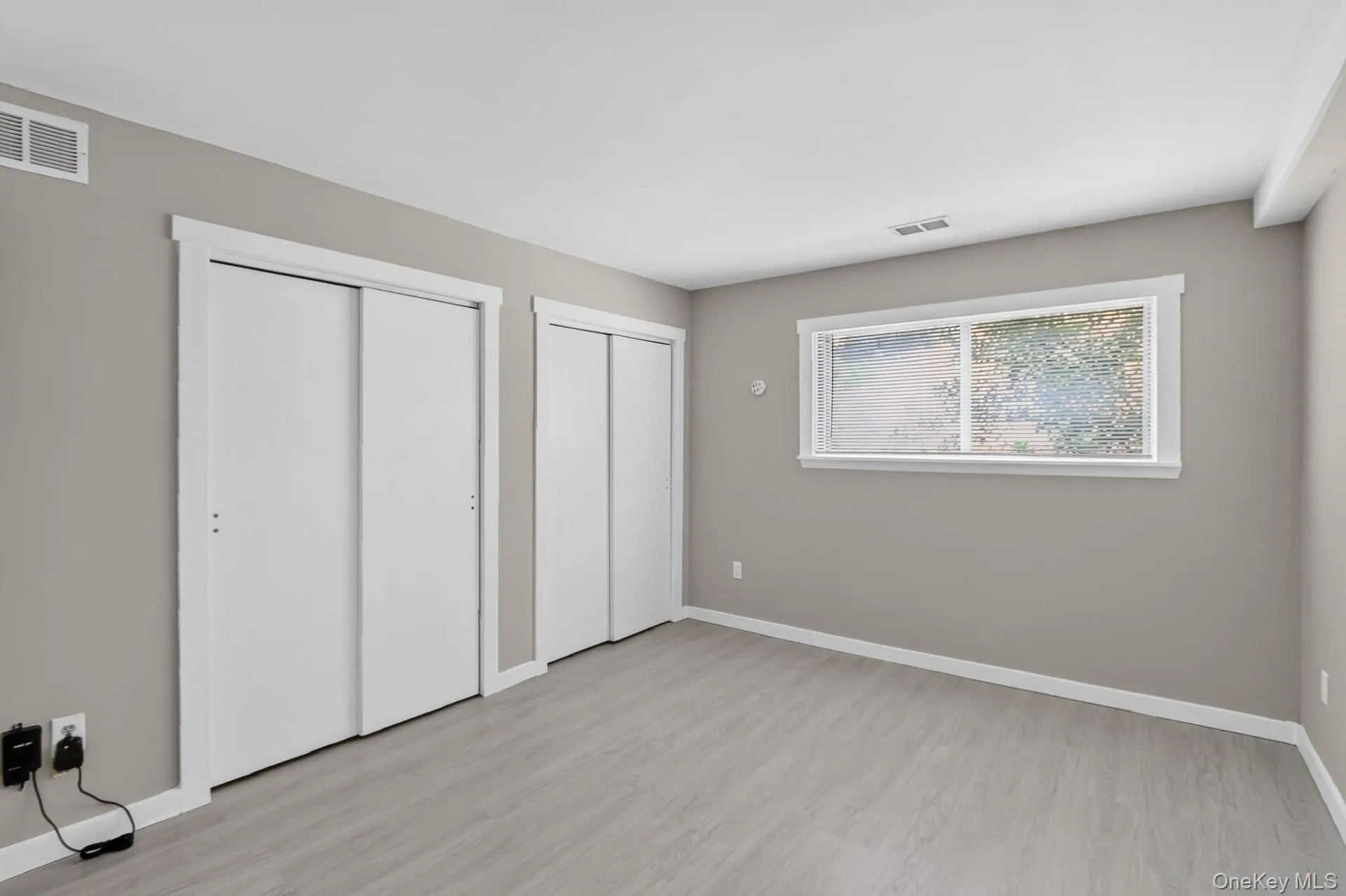 Spacious room featuring light gray walls and wood-finish flooring Spacious room featuring light gray walls and wood-finish flooring