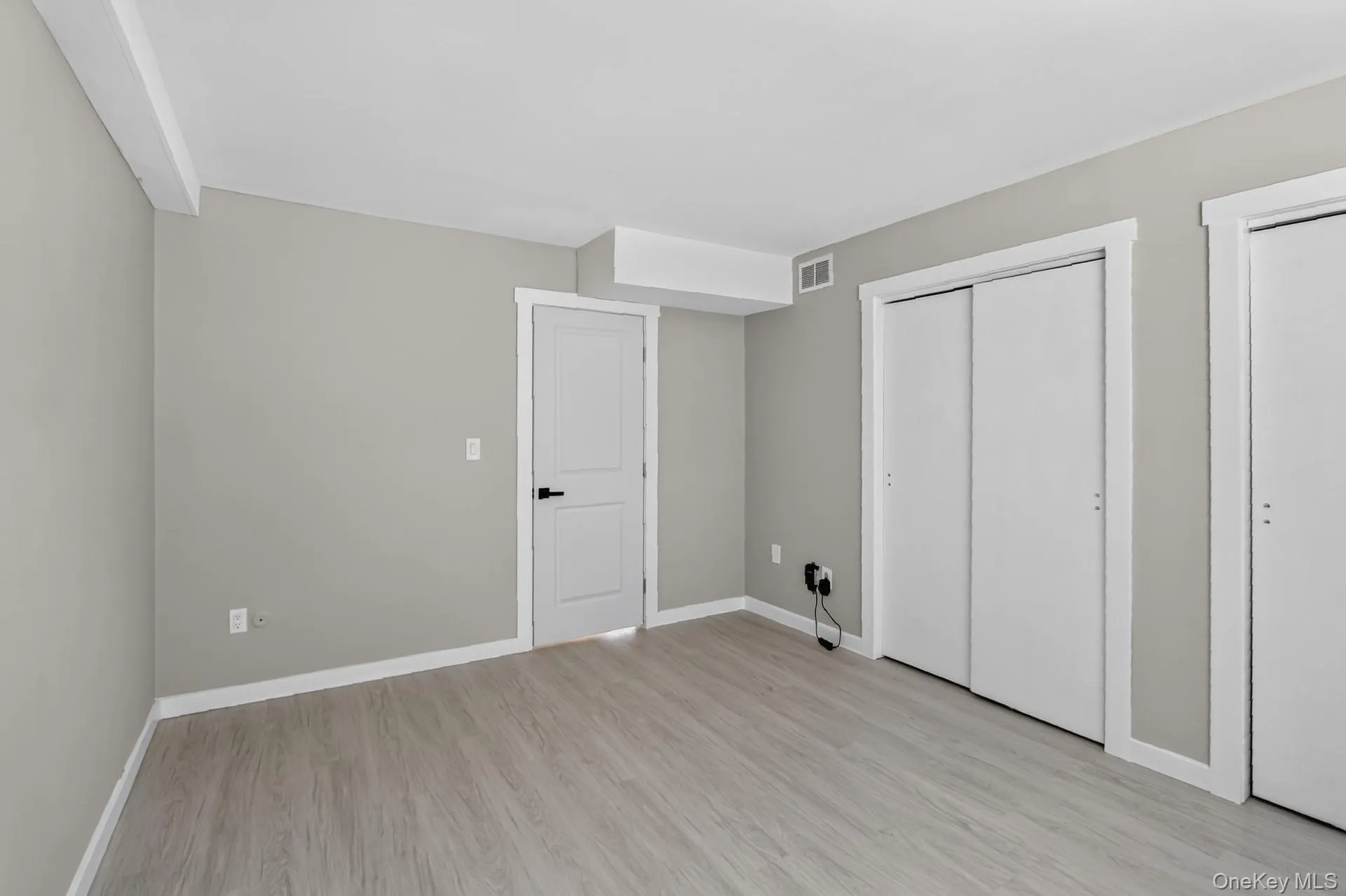 Spacious room featuring wood-finish flooring and neutral wall tones Spacious room featuring wood-finish flooring and neutral wall tones