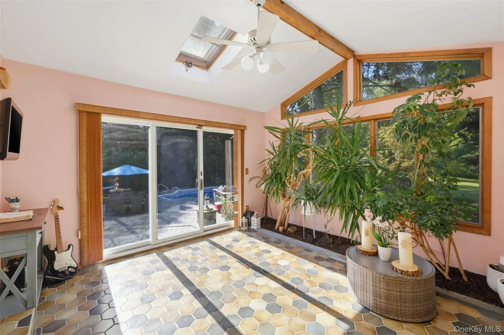 Light-filled sunroom featuring hexagonal tile flooring, a skylight, and exposed wood beams Light-filled sunroom featuring hexagonal tile flooring, a skylight, and exposed wood beams