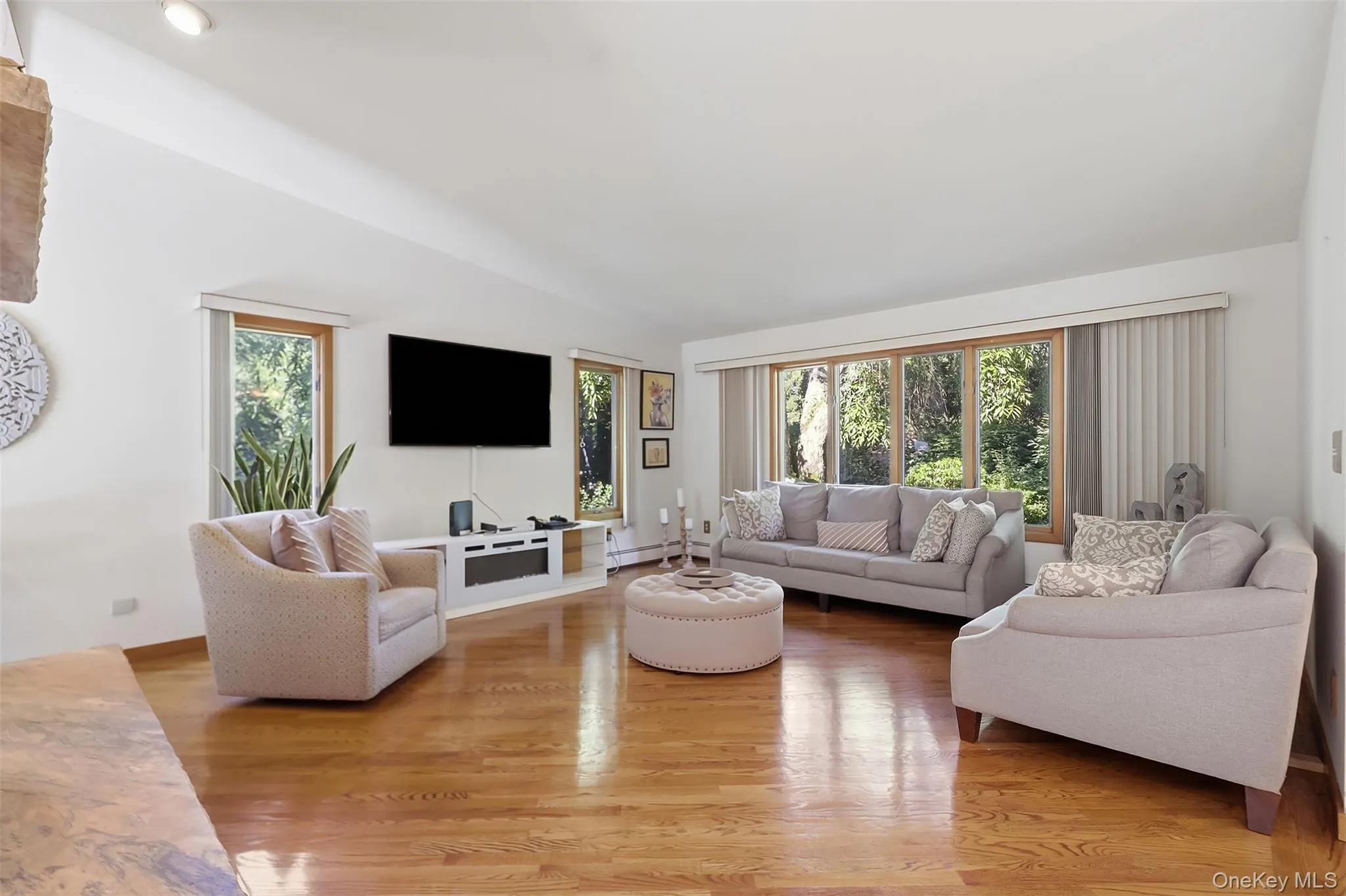 Living area featuring wood-finish flooring, recessed lighting, and expansive windows with natural wood frames Living area featuring wood-finish flooring, recessed lighting, and expansive windows with natural wood frames