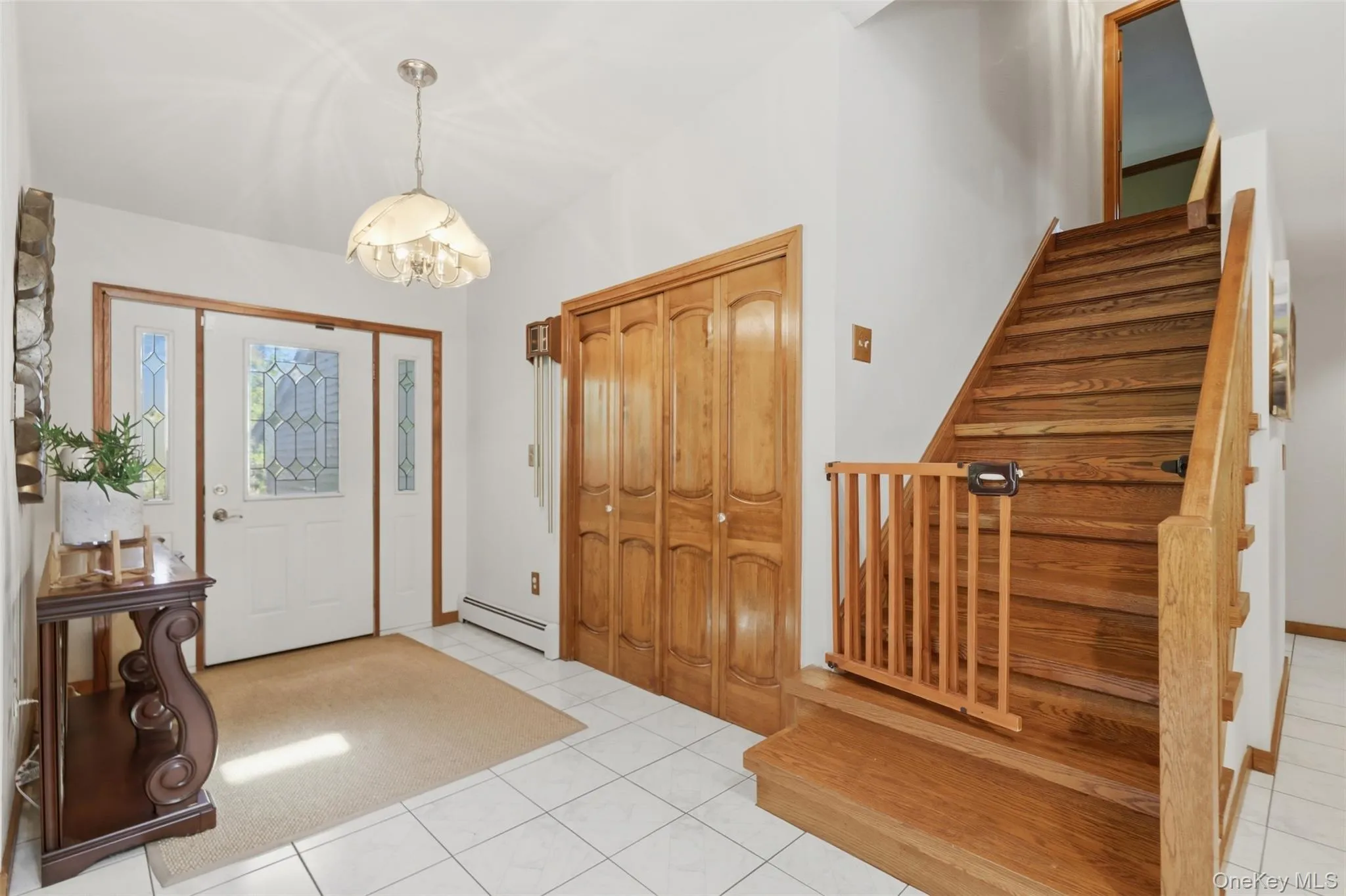 Entryway featuring white tile flooring and a light fixture with frosted glass shades Entryway featuring white tile flooring and a light fixture with frosted glass shades