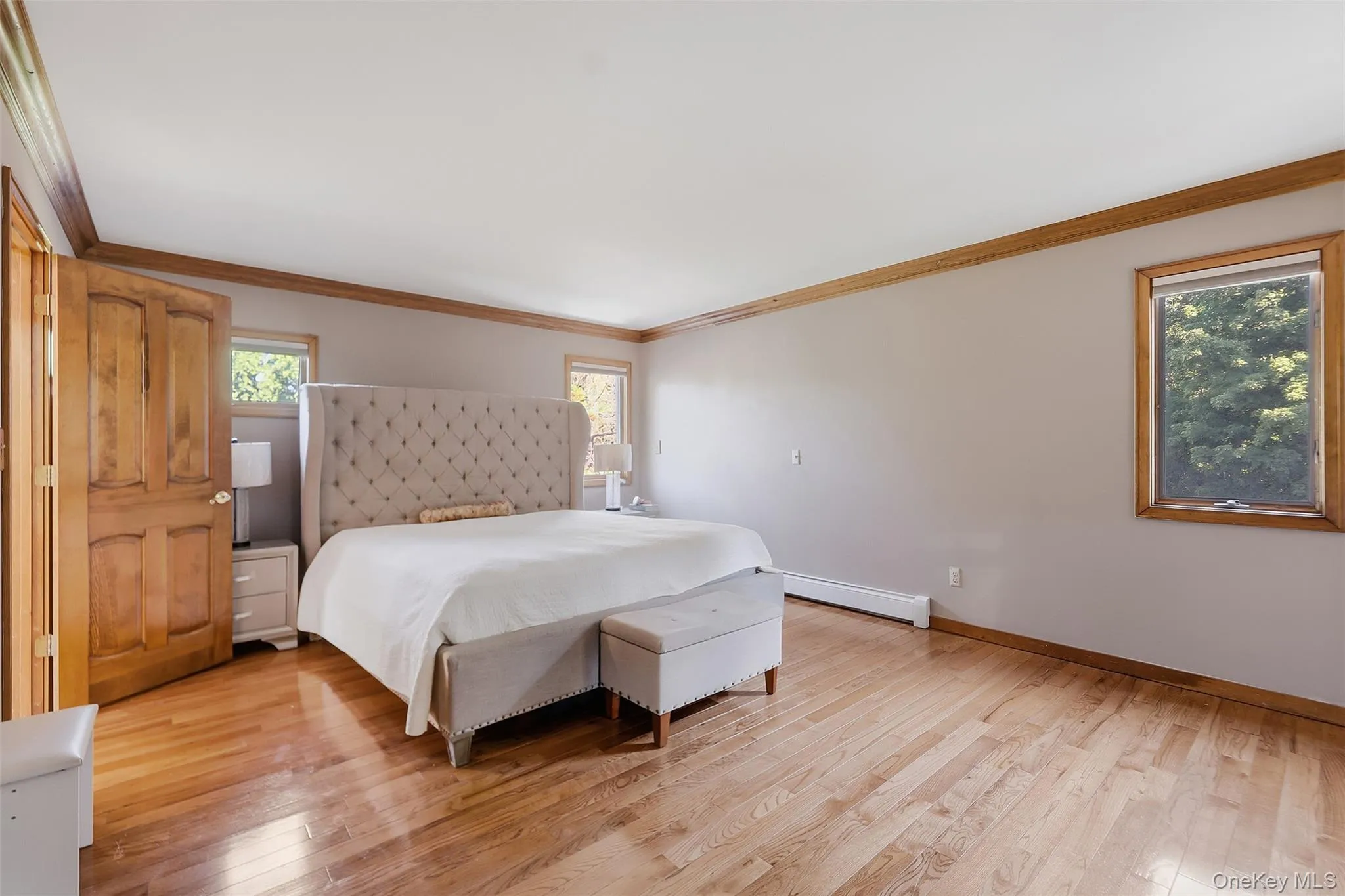 Spacious room featuring wood-finish flooring, natural wood door, wood-framed windows, and wood trim accents Spacious room featuring wood-finish flooring, natural wood door, wood-framed windows, and wood trim accents