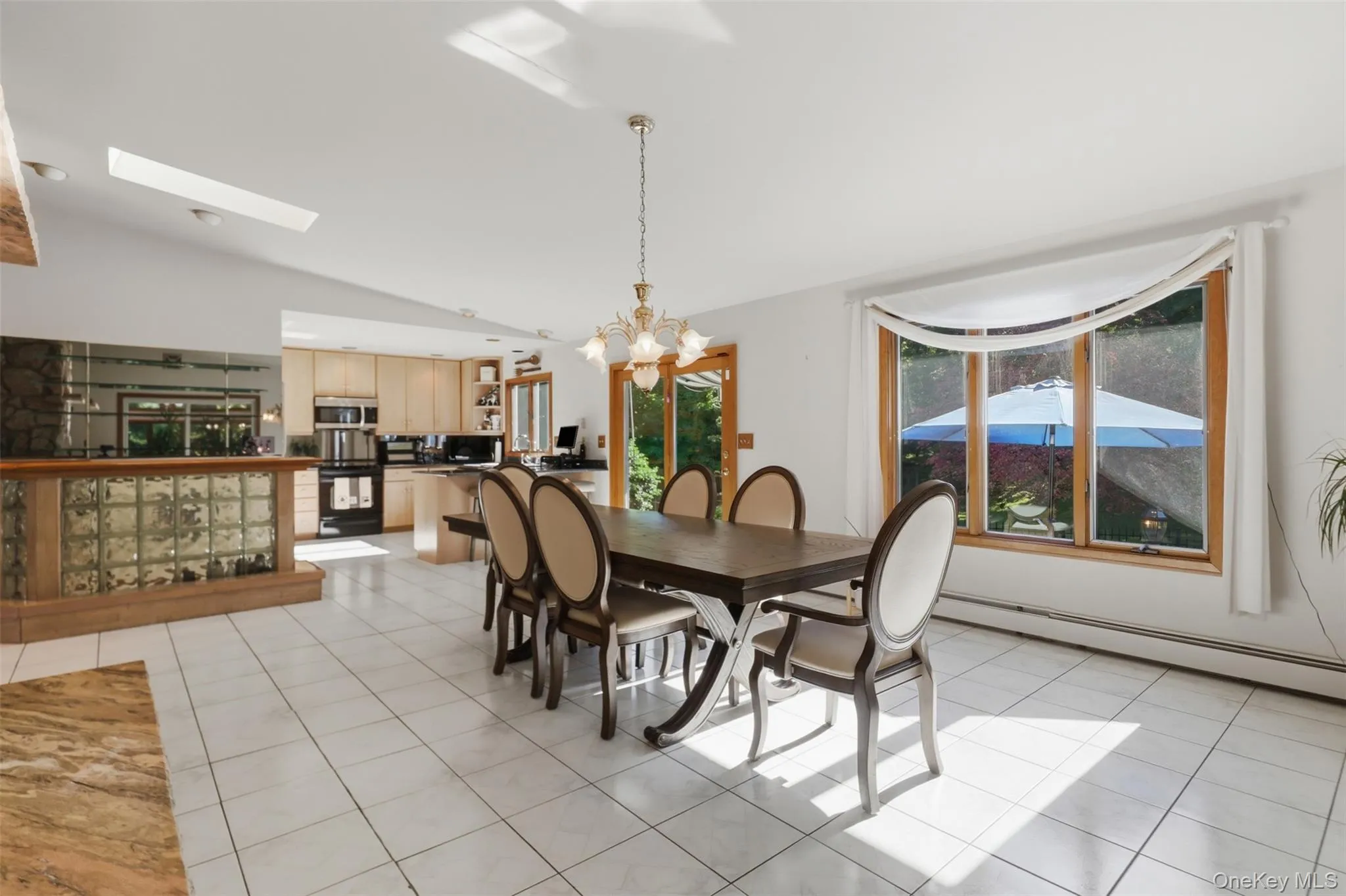 Open-concept dining area featuring tiled flooring and a large picture window Open-concept dining area featuring tiled flooring and a large picture window