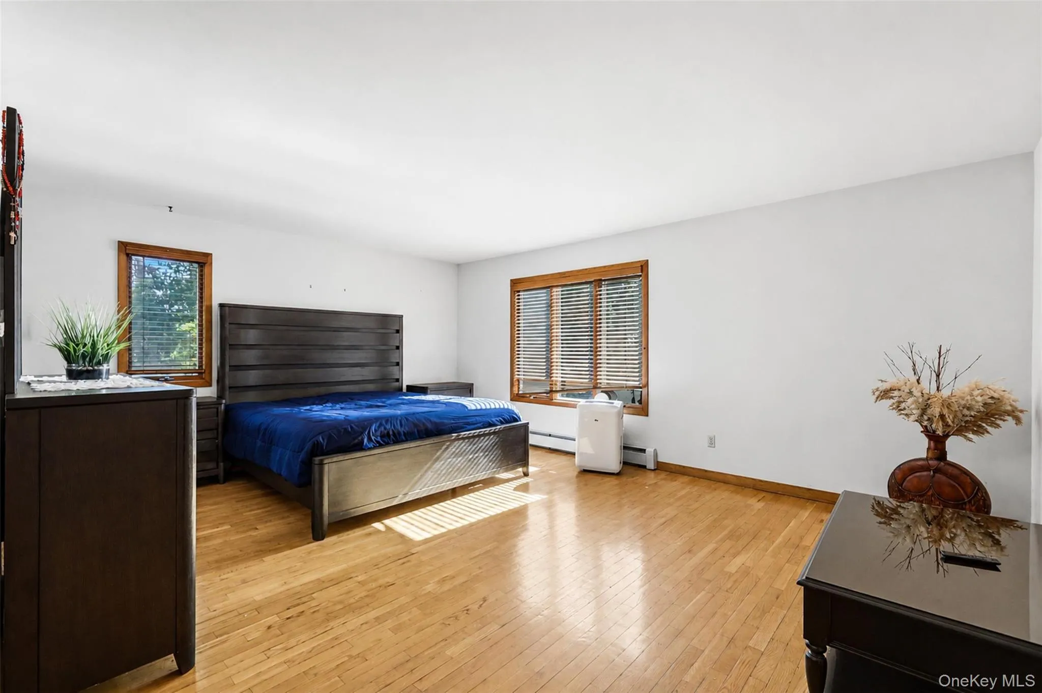 Spacious room featuring hardwood flooring, multiple windows with wood trim and blinds, and a neutral wall color Spacious room featuring hardwood flooring, multiple windows with wood trim and blinds, and a neutral wall color