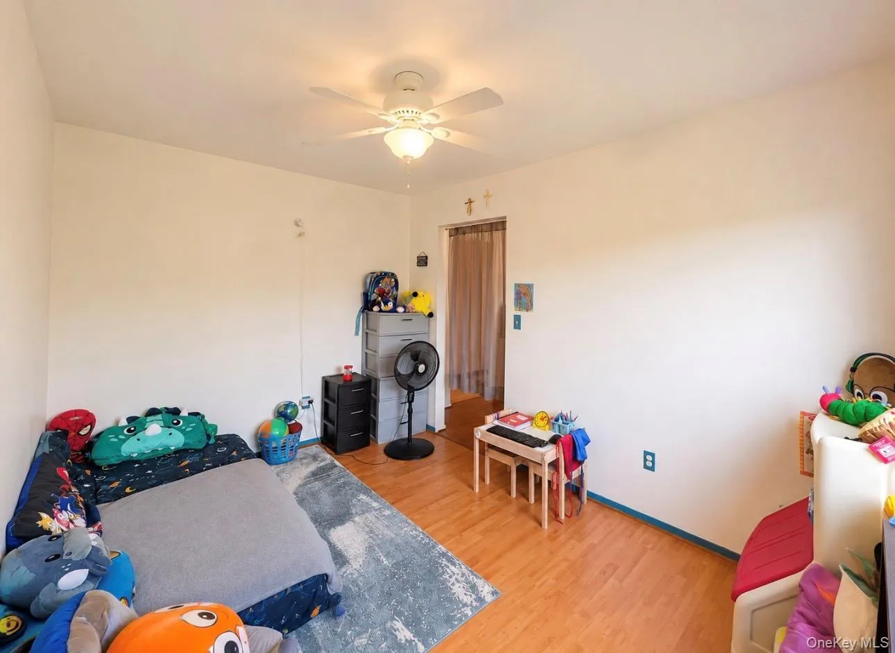 Room featuring wood-finish flooring, light-toned walls, and a ceiling fan with integrated lighting Room featuring wood-finish flooring, light-toned walls, and a ceiling fan with integrated lighting