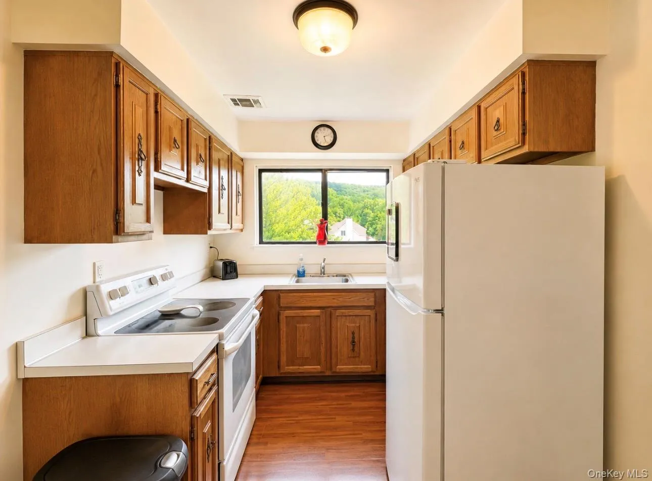 Kitchen featuring wood-finish cabinetry, white countertops, and wood-finish flooring Kitchen featuring wood-finish cabinetry, white countertops, and wood-finish flooring