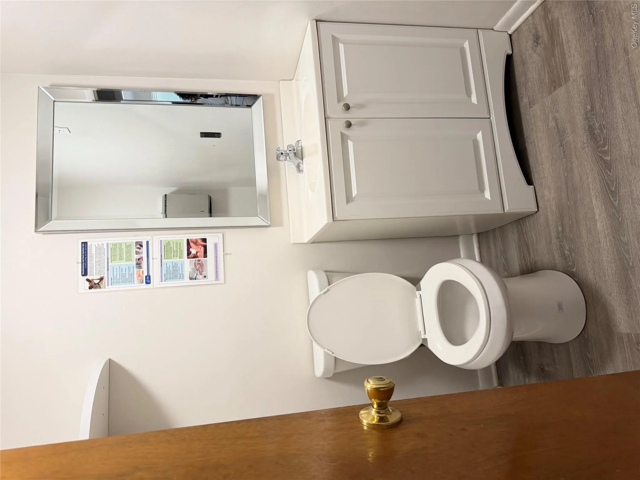 Bathroom featuring a white toilet, white vanity with integrated sink, chrome faucet, and a rectangular mirror with a beveled frame Bathroom featuring a white toilet, white vanity with integrated sink, chrome faucet, and a rectangular mirror with a beveled frame