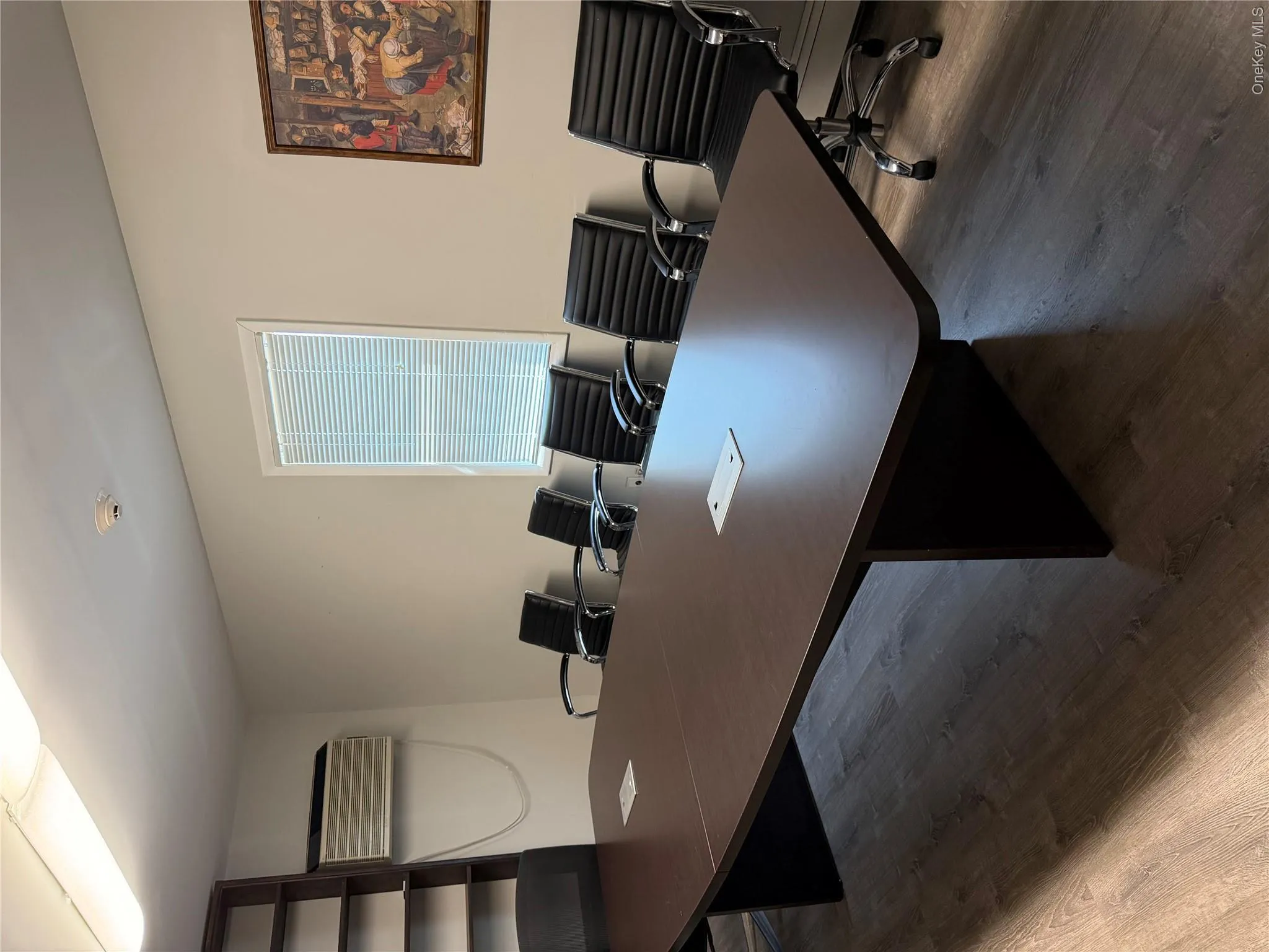 Conference room featuring a large dark wood-finish table with integrated power outlets, complementing wood-finish flooring, and a built-in shelving unit Conference room featuring a large dark wood-finish table with integrated power outlets, complementing wood-finish flooring, and a built-in shelving unit