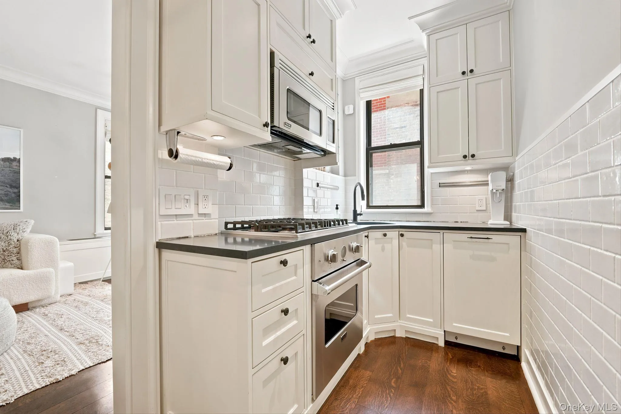 Kitchen featuring white shaker cabinetry, stainless steel appliances, dark countertops, and subway tile backsplash Kitchen featuring white shaker cabinetry, stainless steel appliances, dark countertops, and subway tile backsplash