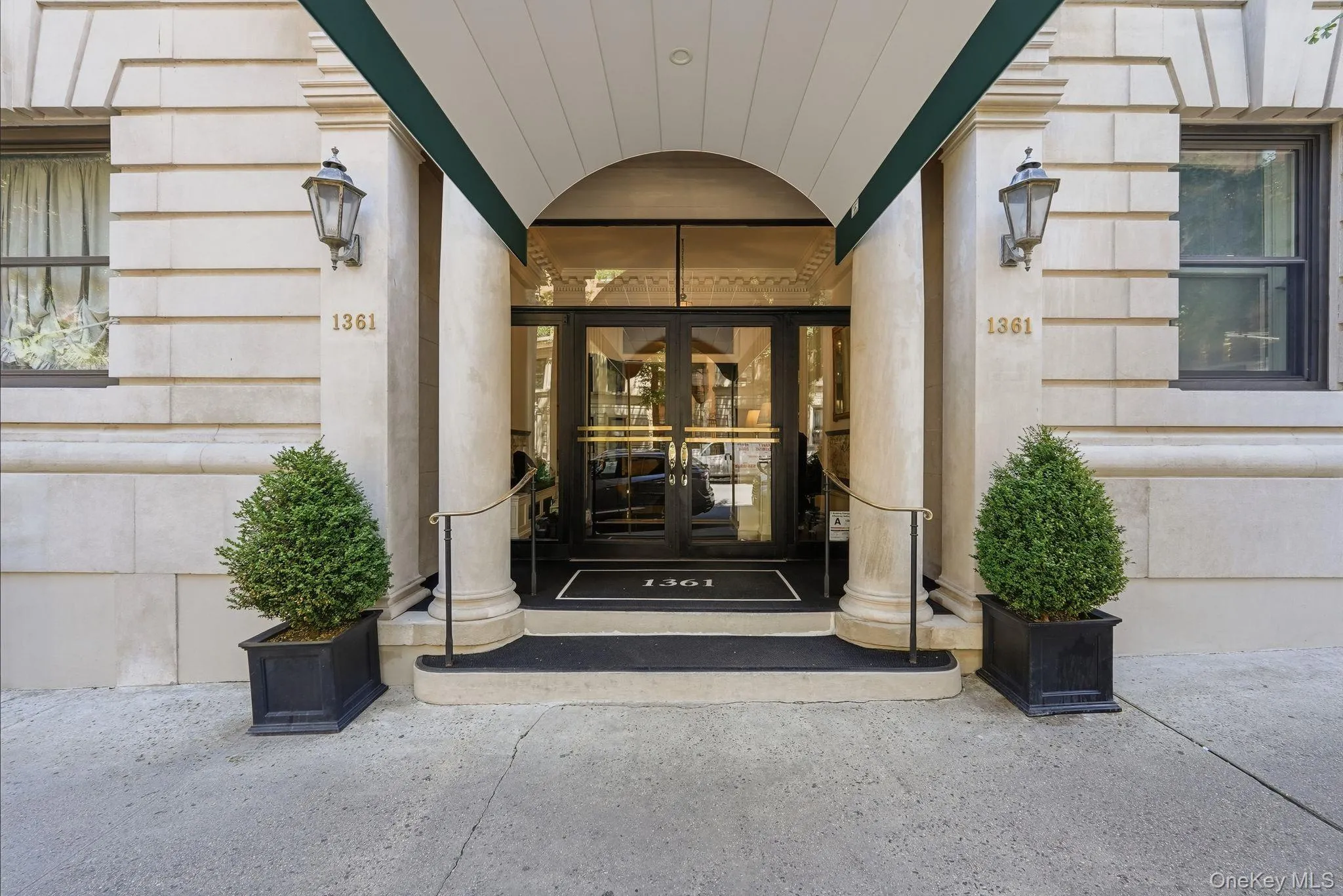 Building entrance featuring a stone facade, arched portico, and decorative outdoor sconces Building entrance featuring a stone facade, arched portico, and decorative outdoor sconces