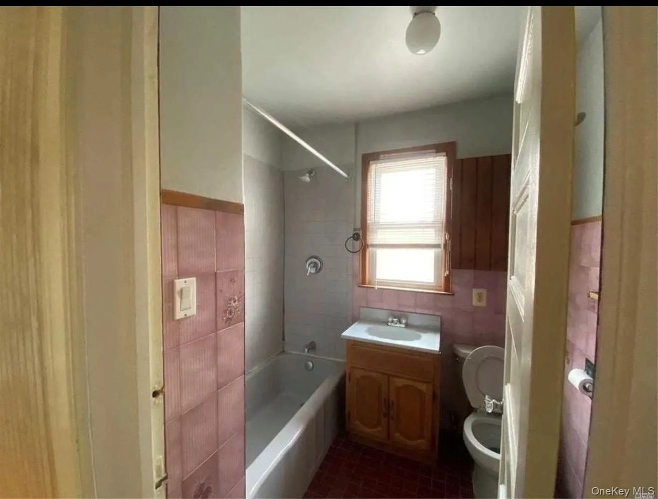 Bathroom featuring a bathtub with shower head, vanity with sink, window with blinds, and tiled walls Bathroom featuring a bathtub with shower head, vanity with sink, window with blinds, and tiled walls