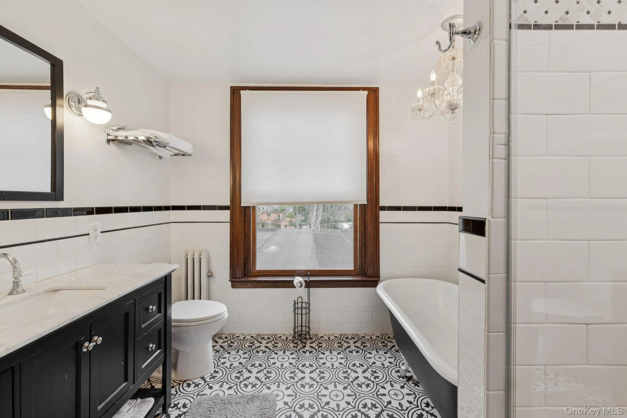 Bathroom featuring tile walls, a wainscoted wall, a freestanding bath, radiator, and vanity Bathroom featuring tile walls, a wainscoted wall, a freestanding bath, radiator, and vanity