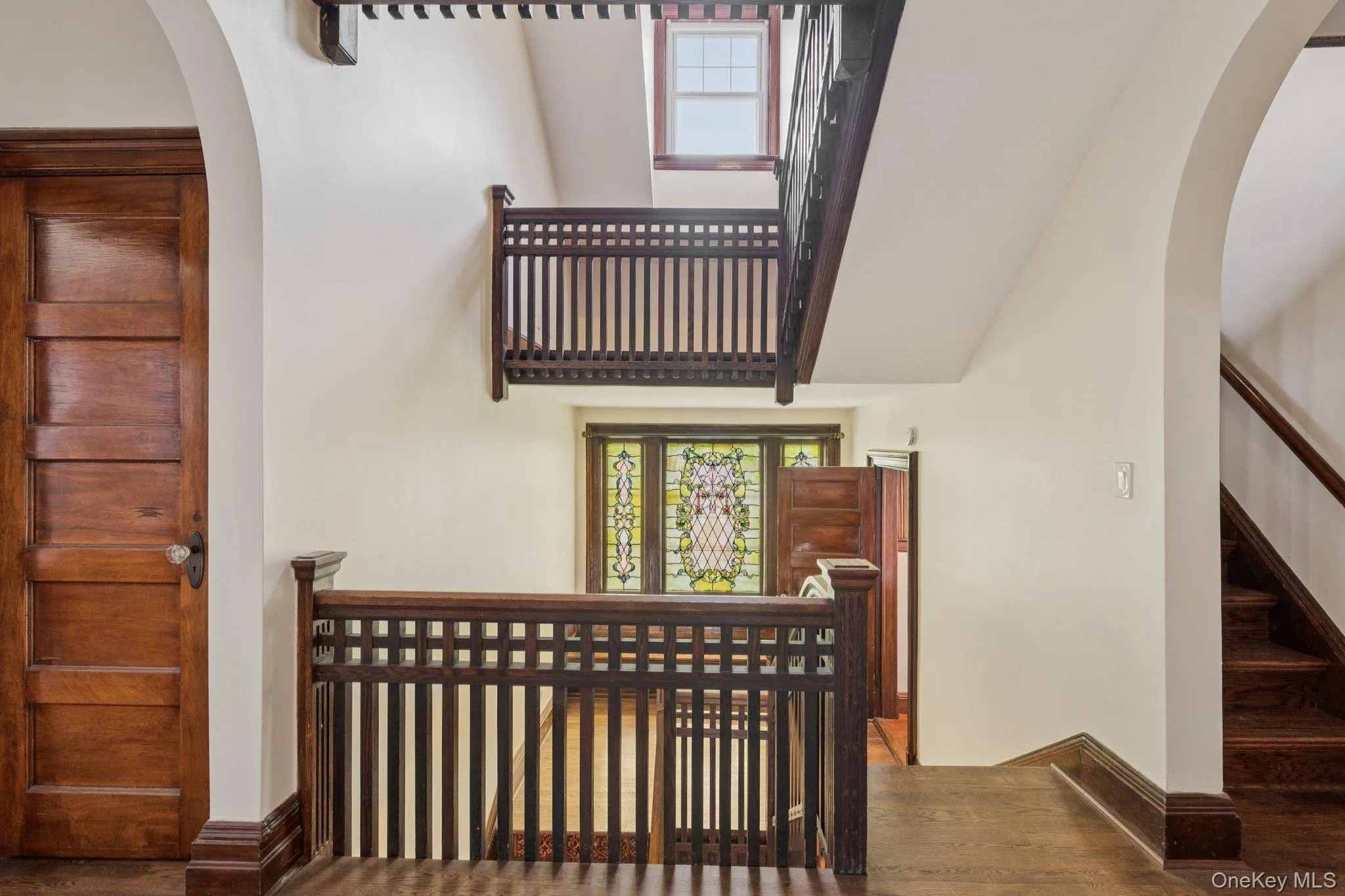 Staircase with arched walkways, plenty of natural light, wood finished floors, and a high ceiling Staircase with arched walkways, plenty of natural light, wood finished floors, and a high ceiling