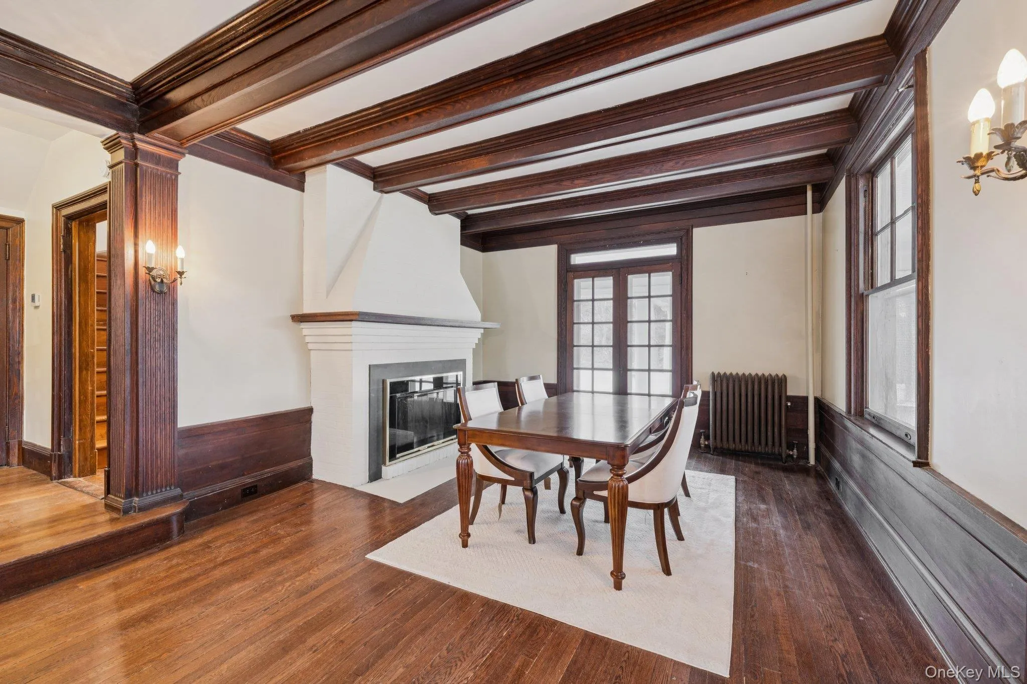 Dining area featuring radiator, dark wood finished floors, a fireplace, french doors, and ornamental molding Dining area featuring radiator, dark wood finished floors, a fireplace, french doors, and ornamental molding