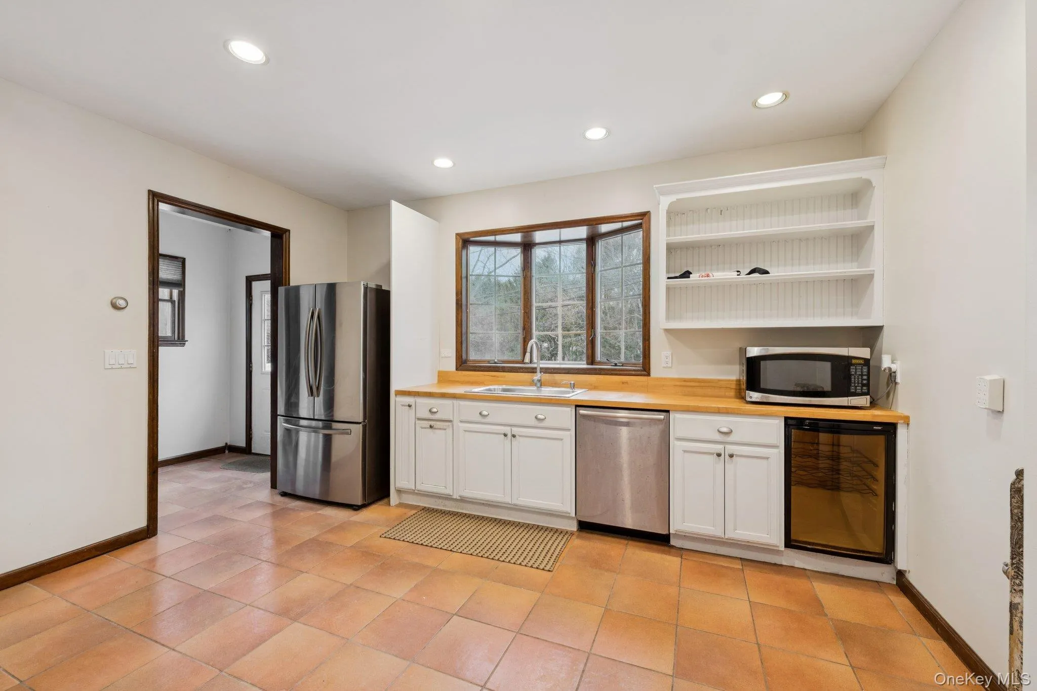 Kitchen with white cabinets, stainless steel appliances, open shelves, recessed lighting, and beverage cooler Kitchen with white cabinets, stainless steel appliances, open shelves, recessed lighting, and beverage cooler