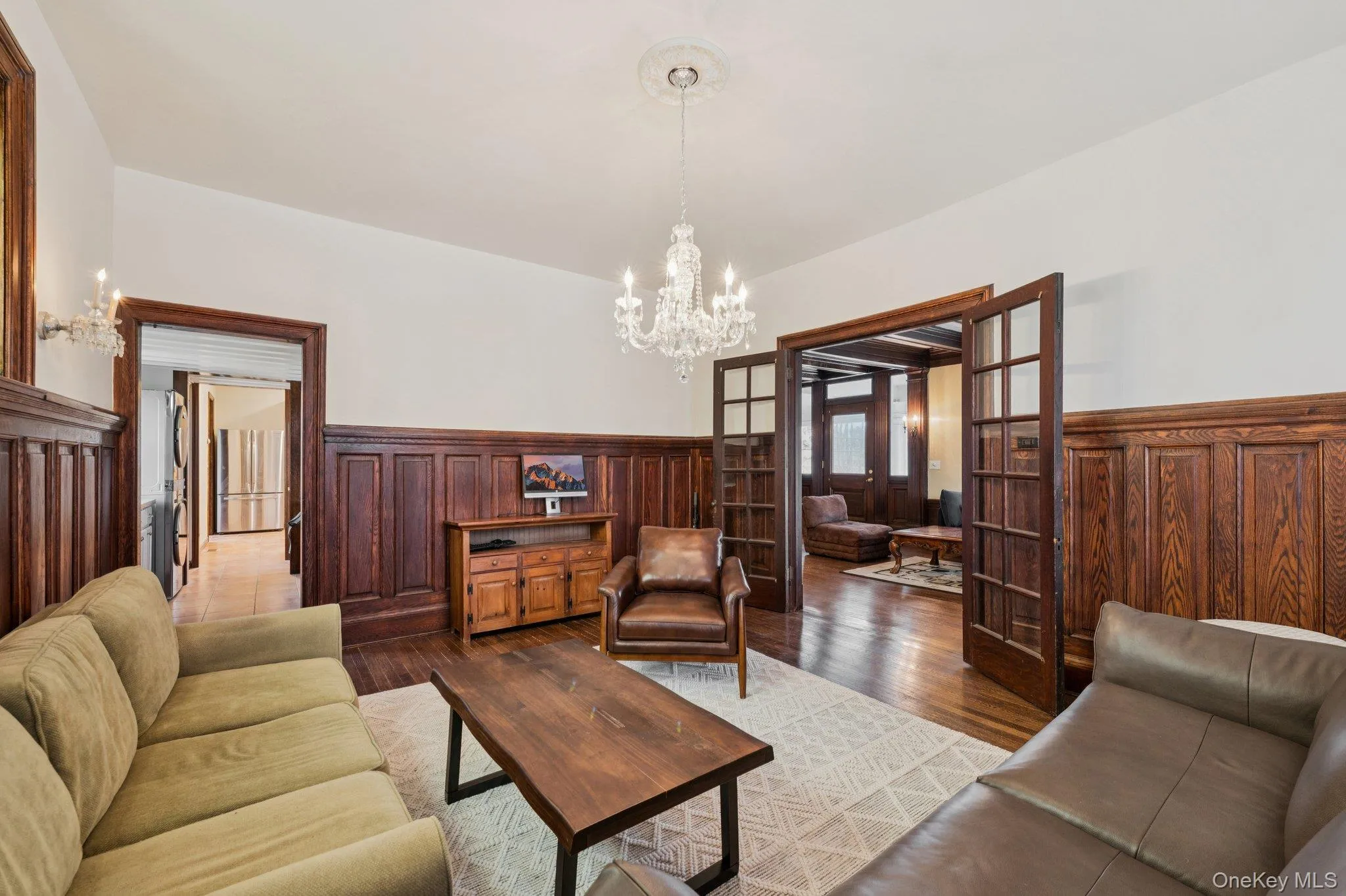 Living room with a wainscoted wall, a chandelier, french doors, and hardwood / wood-style floors Living room with a wainscoted wall, a chandelier, french doors, and hardwood / wood-style floors