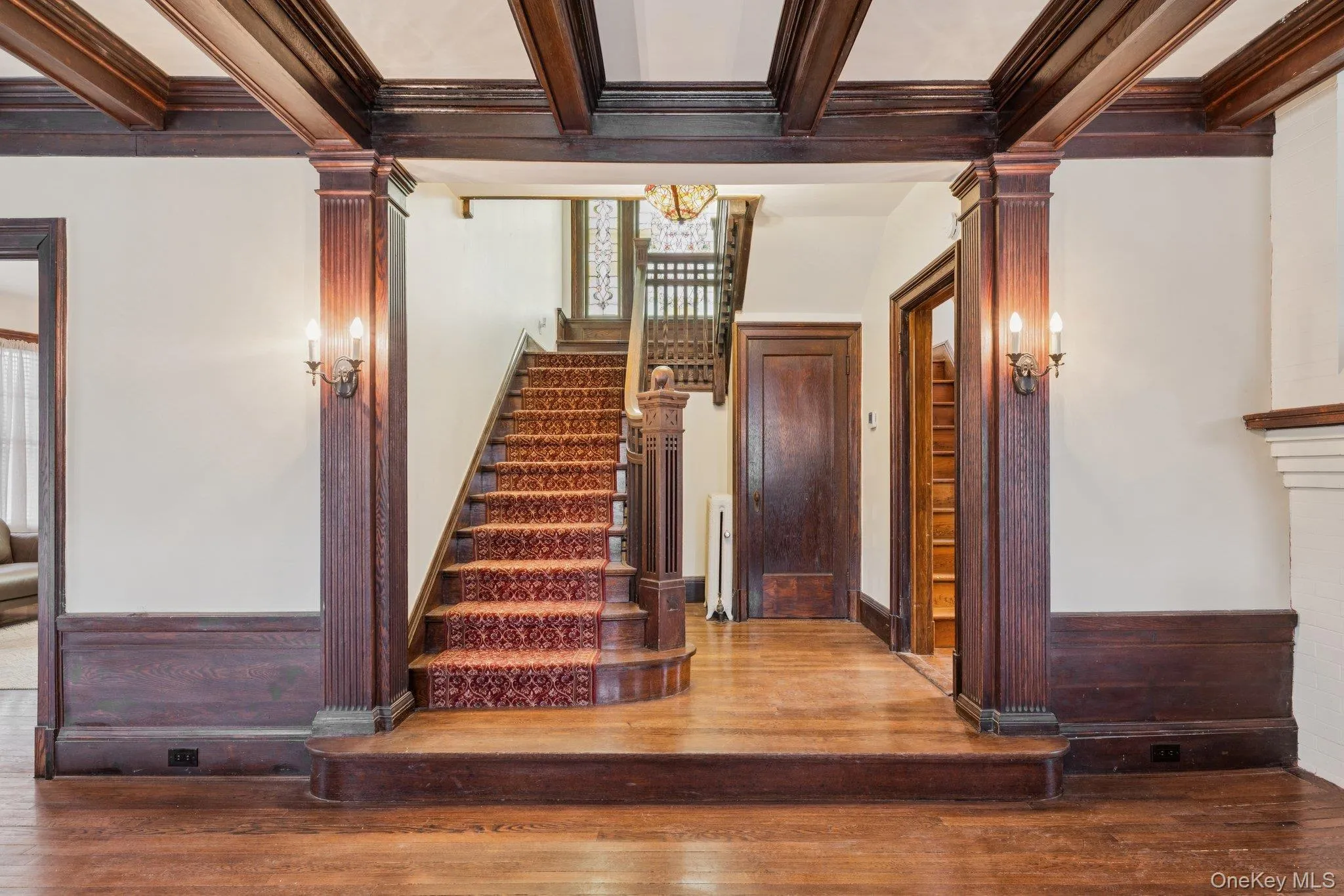 Stairs with ornate columns, hardwood / wood-style flooring, beam ceiling, radiator heating unit, and ornamental molding Stairs with ornate columns, hardwood / wood-style flooring, beam ceiling, radiator heating unit, and ornamental molding