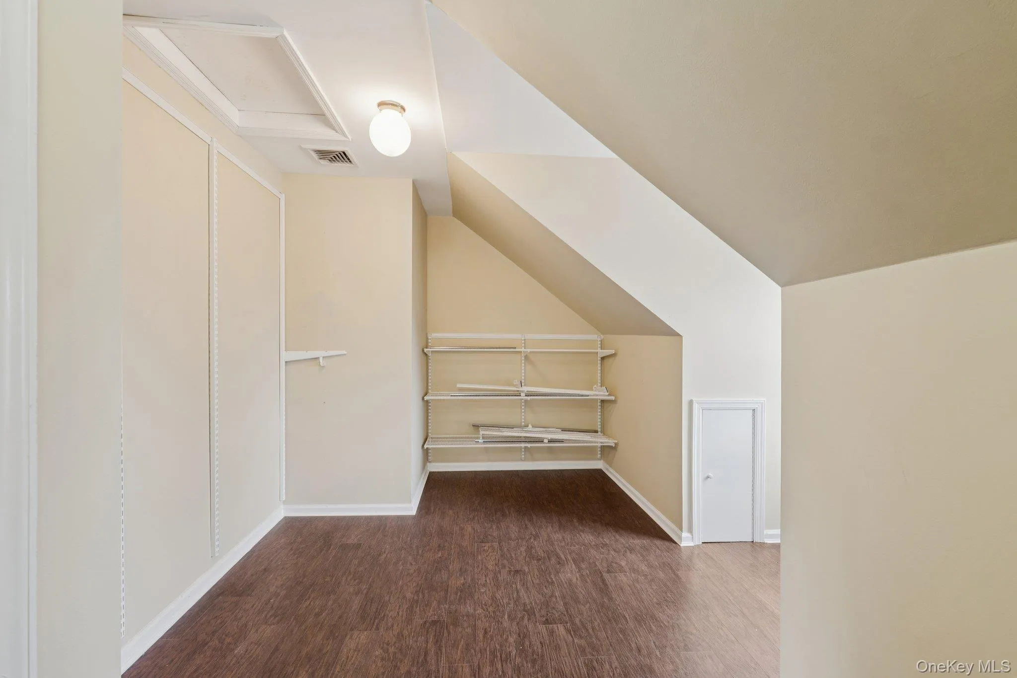 Bonus room featuring dark wood finished floors, lofted ceiling, and attic access Bonus room featuring dark wood finished floors, lofted ceiling, and attic access