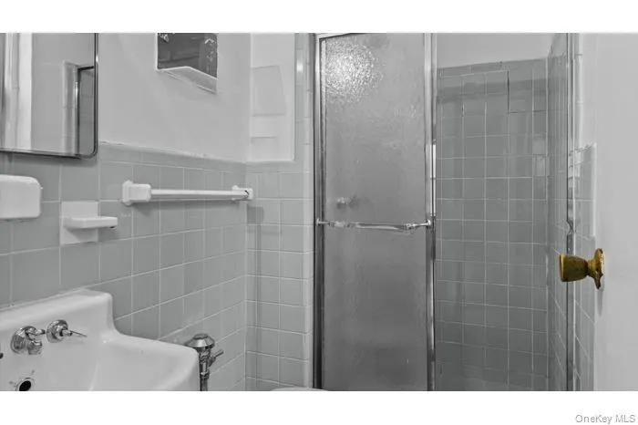 Bathroom featuring a stall shower and tile walls Bathroom featuring a stall shower and tile walls